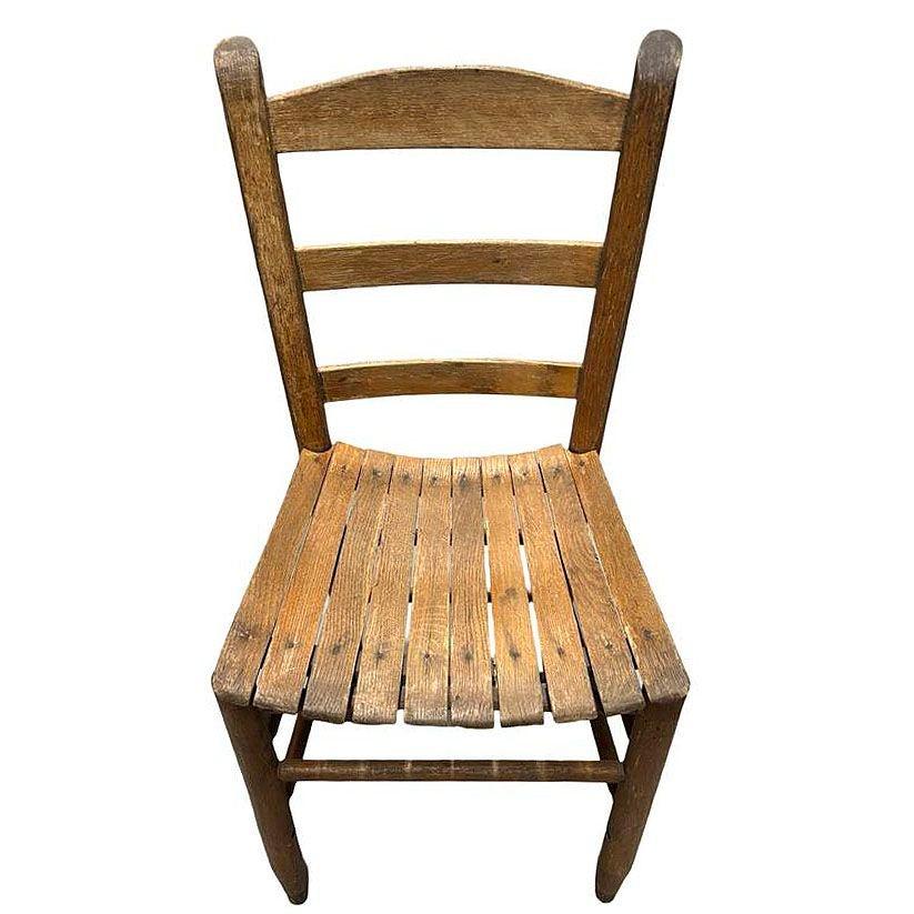Cette chaise d'appoint en bois antique à dossier en échelle et assise en lattes présente un caractère usé par le temps et les intempéries. La chaise présente un design classique à dossier en échelle, où les solides lattes de bois ont magnifiquement