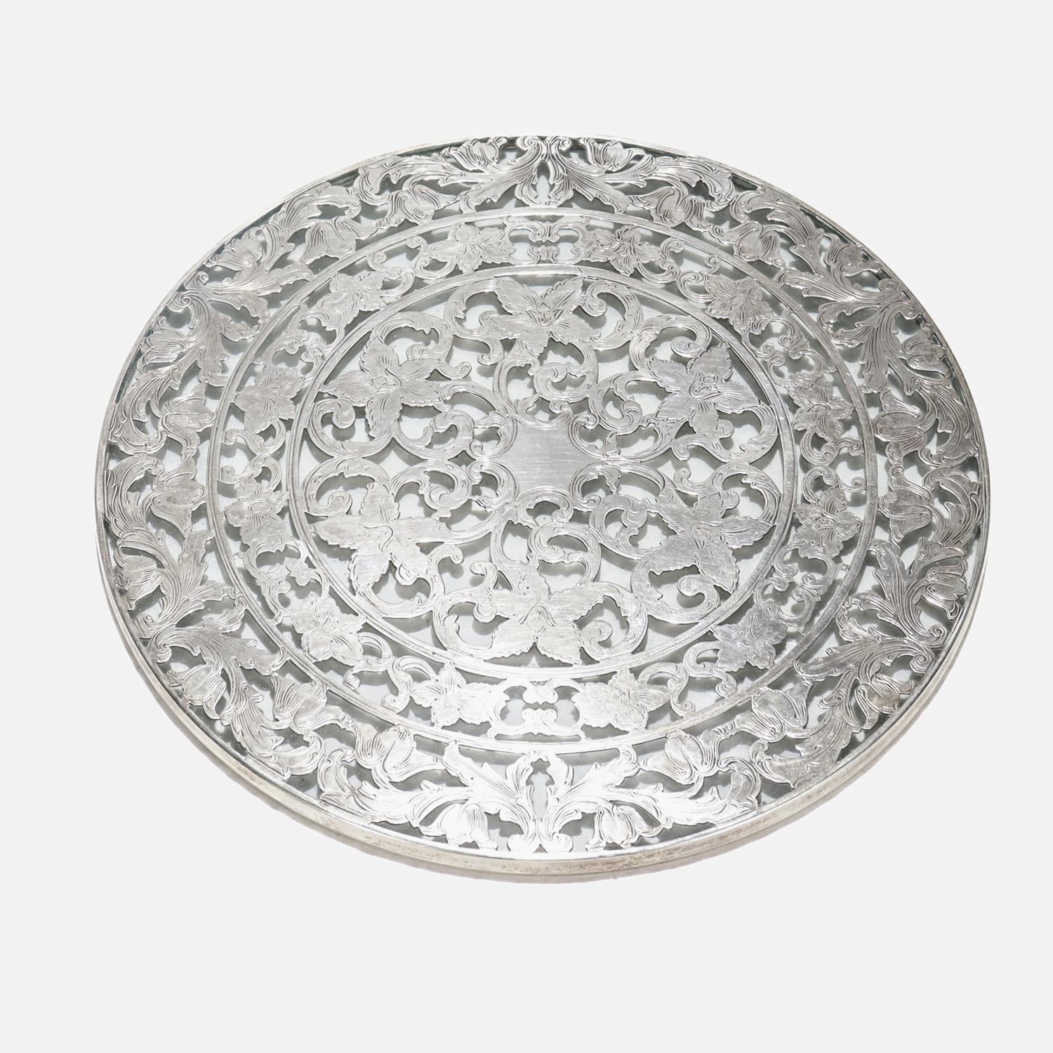 A fine wine coaster or trivet.

By the Webster Co. of North Attleboro, MA.

With a sterling silver overlay in a floral pattern on a glass base.

Marked to the rim for Webster / Sterling / Webster's maker's mark.

Simply a wonderful coaster or