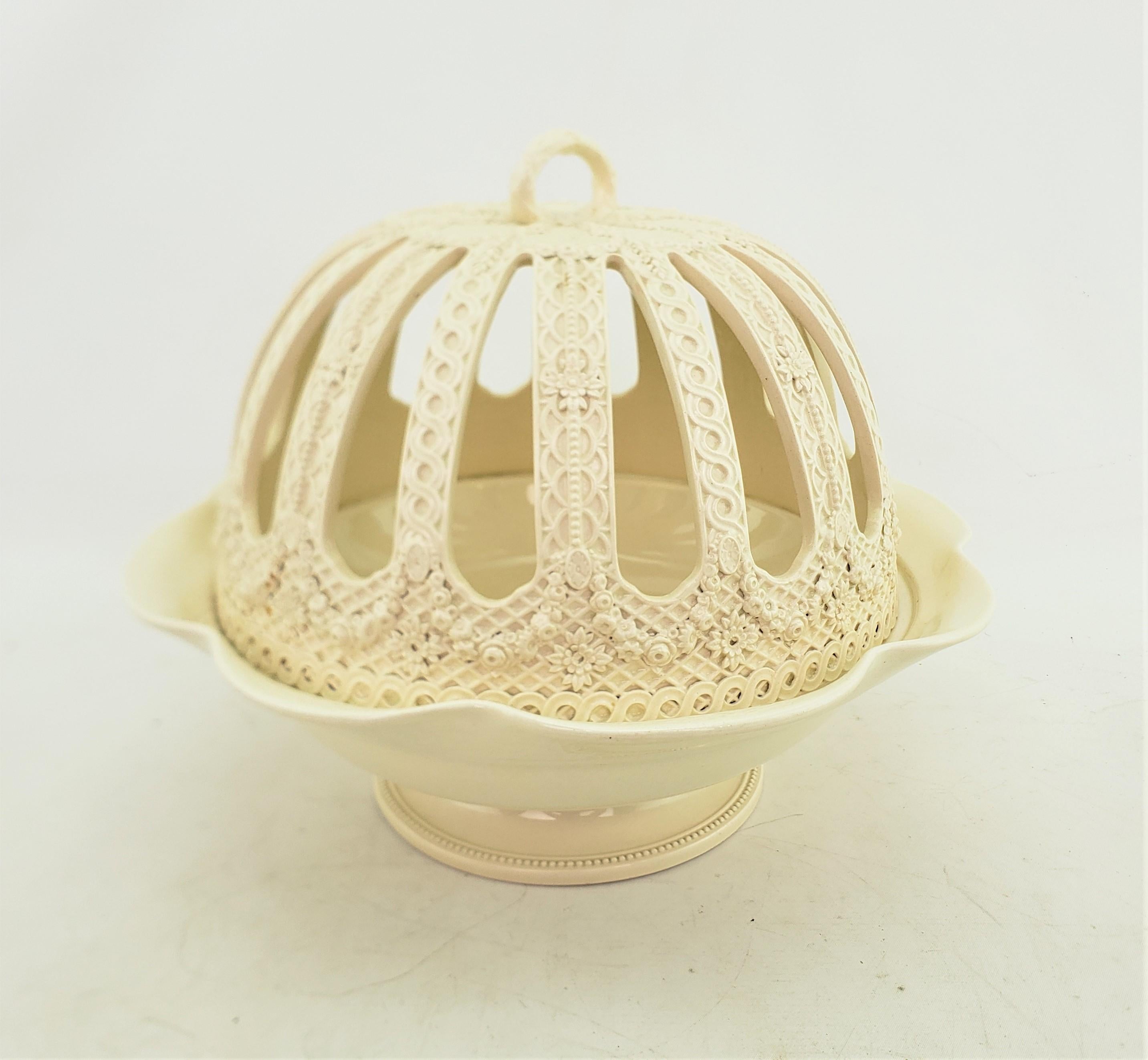 This antique covered bowl was made by the Wedgwood factory of England in approximately 1920 and done in a Georgian style. This orange bowl is composed of creamware ceramic, also known as Queen's Ware and has a bottom bowl with a scalloped edge with