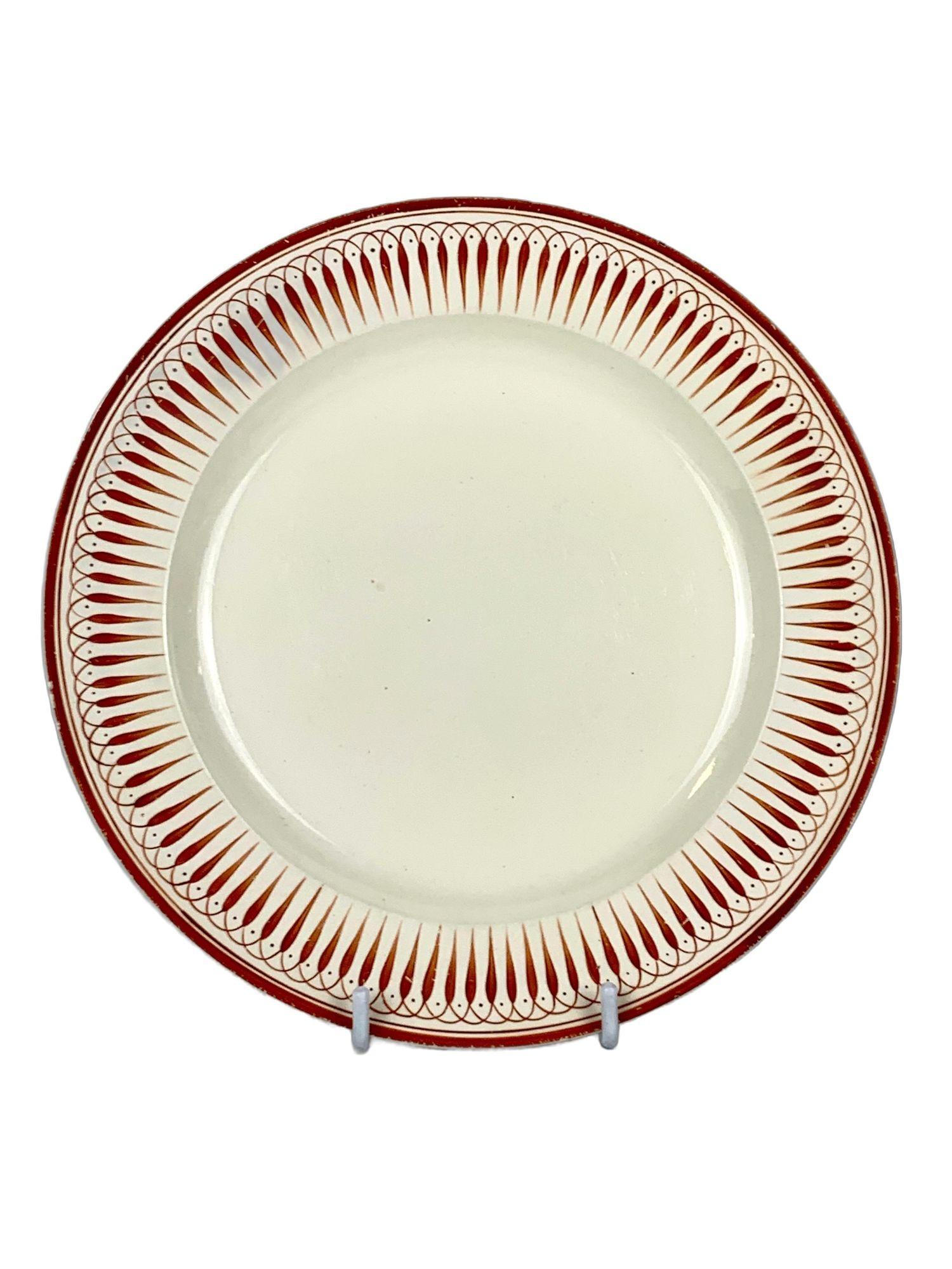 This Wedgwood creamware plate and handled cup were made in England circa 1790.
Both pieces feature a hand-painted border of radiating neoclassical design, rendered in striking red and cobalt blue.
The rhythmic, symmetrical pattern is framed by a