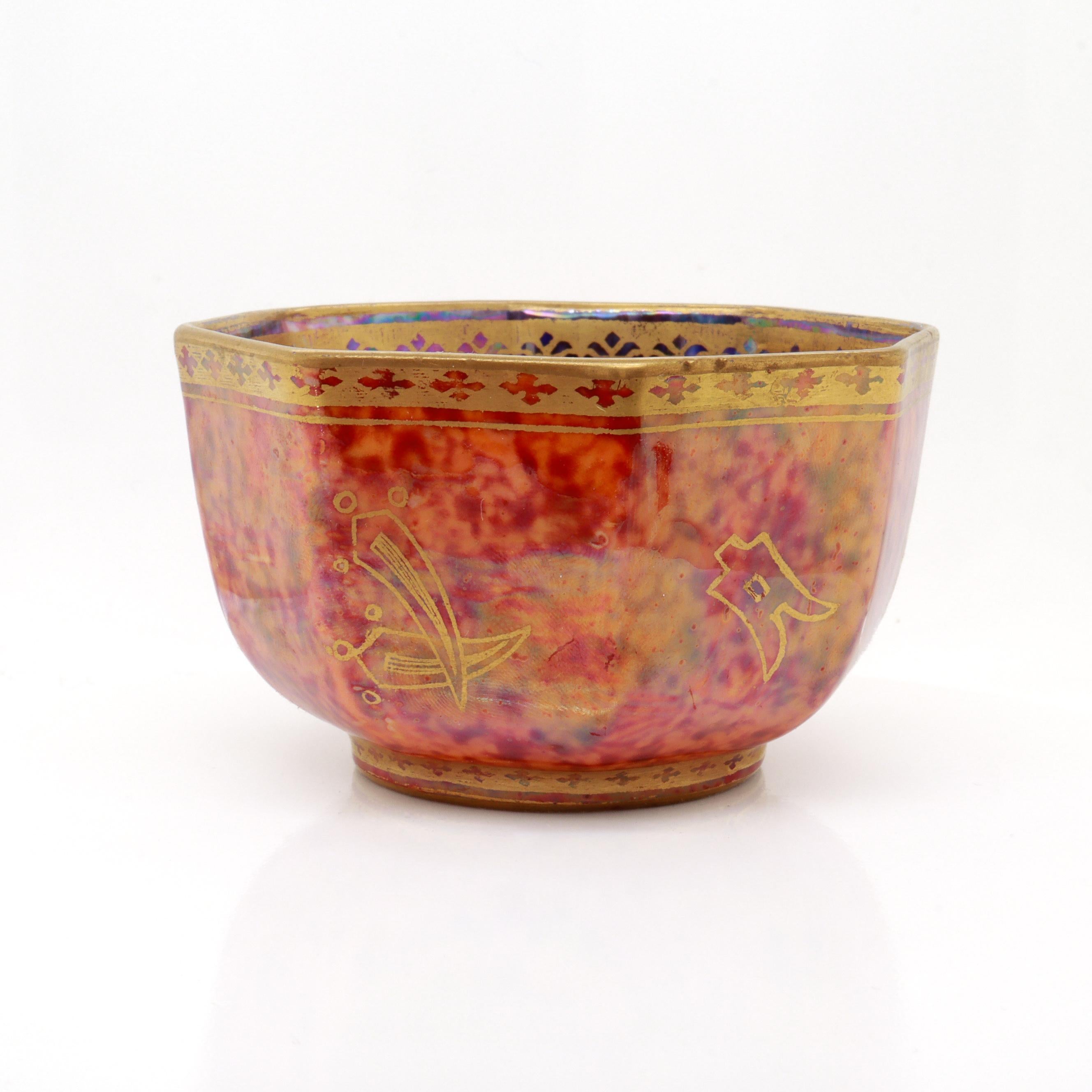 A fine antique, diminutive English lustreware porcelain tea bowl or cup.

By Wedgwood.

Pattern no. Z4825.

Designed by Daisy Makeig-Jones. 

With a gilt stylized butterfly and Chinese sybmols on a mottled orange exterior and a mottled blue interior