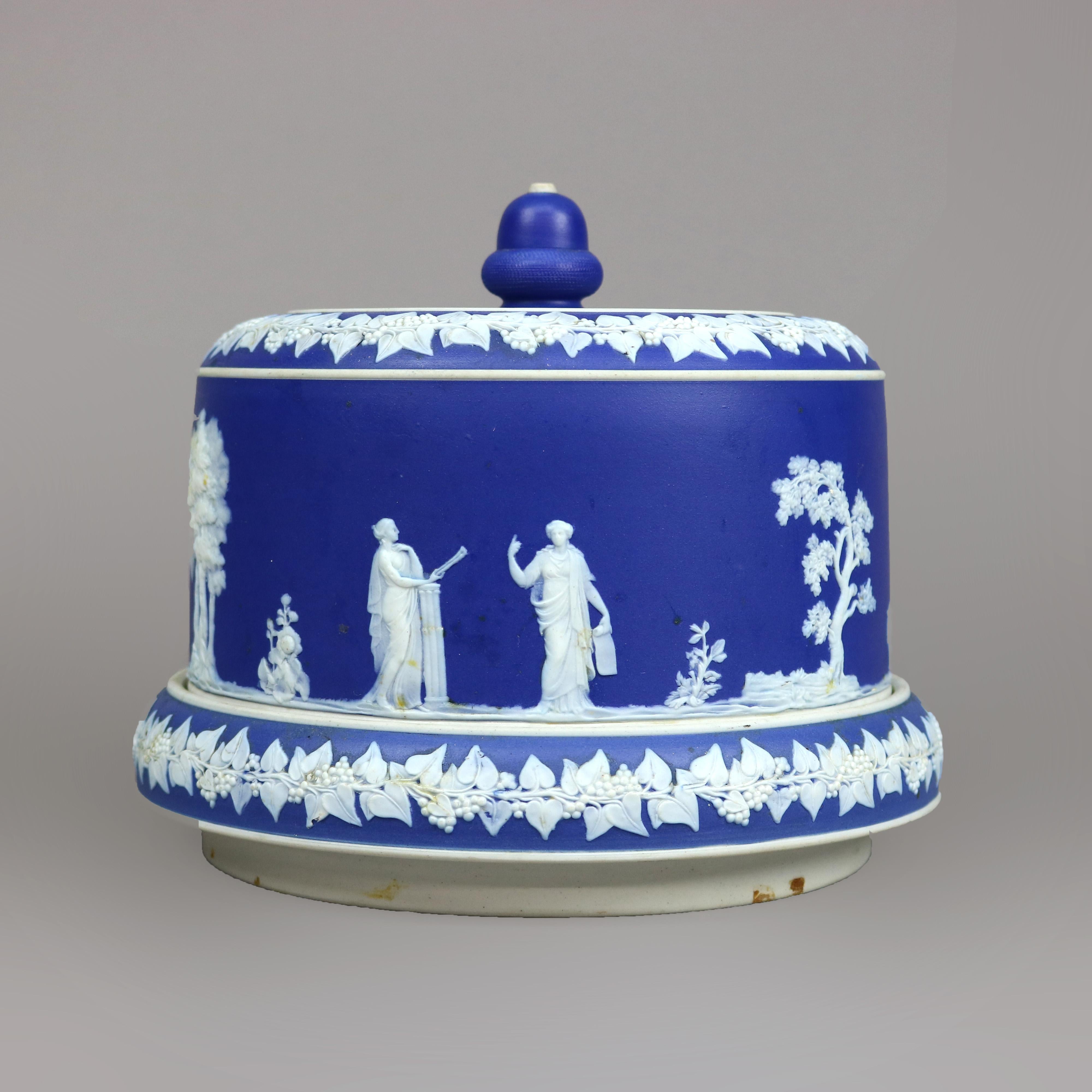 An antique and large English jasperware cheese keeper in the attributed to Wedgwood offers bisque porcelain construction with white Classical cameo scene with figures in relief on a blue ground, unmarked, 19th century

Measures - 8'' H x 9.25'' W