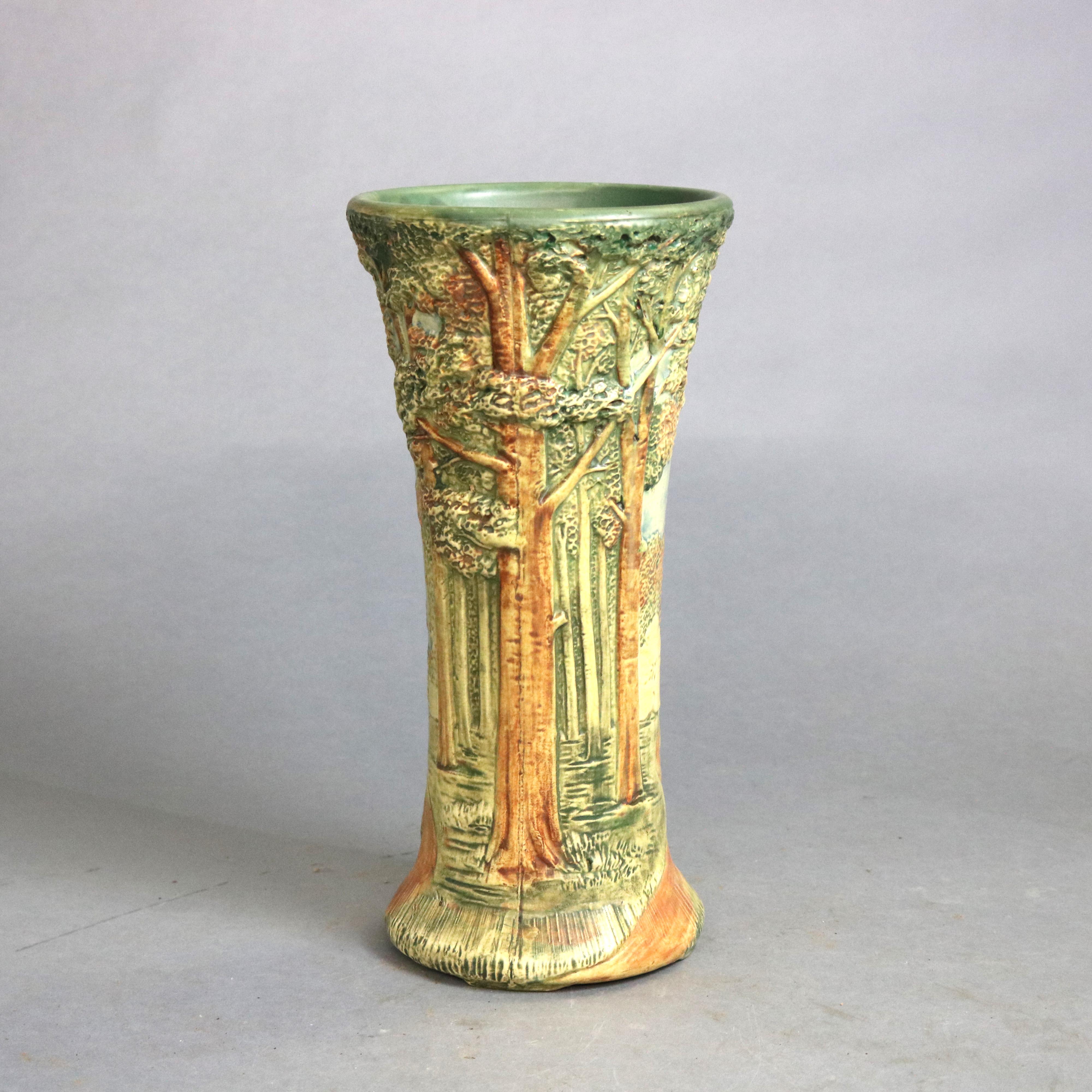 An antique vase by Weller in the Forest pattern offers art pottery construction in hourglass form with polychrome all-around landscape scene in relief, unsigned, circa 1930

Measures - 13.5'' H x 6.5'' W x 6.5'' D.
