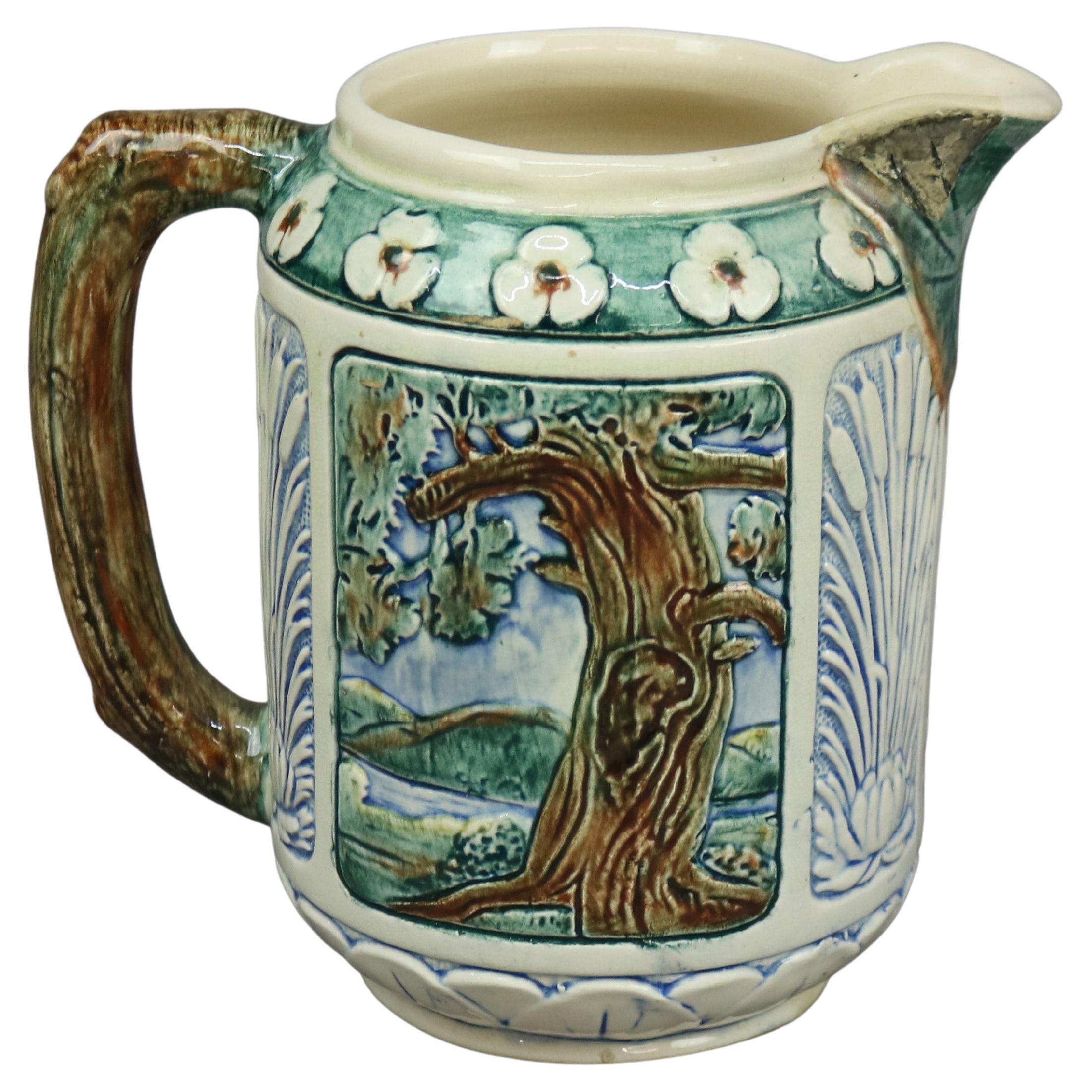 An antique pitcher by Weller offers art pottery construction with reserves having king fisher bird and tree in woodland setting, stick form handle and stylized flowers, signed on base as photographed, c 1930

Measures - 8.5''H x 5.75''W x 8.75''D.