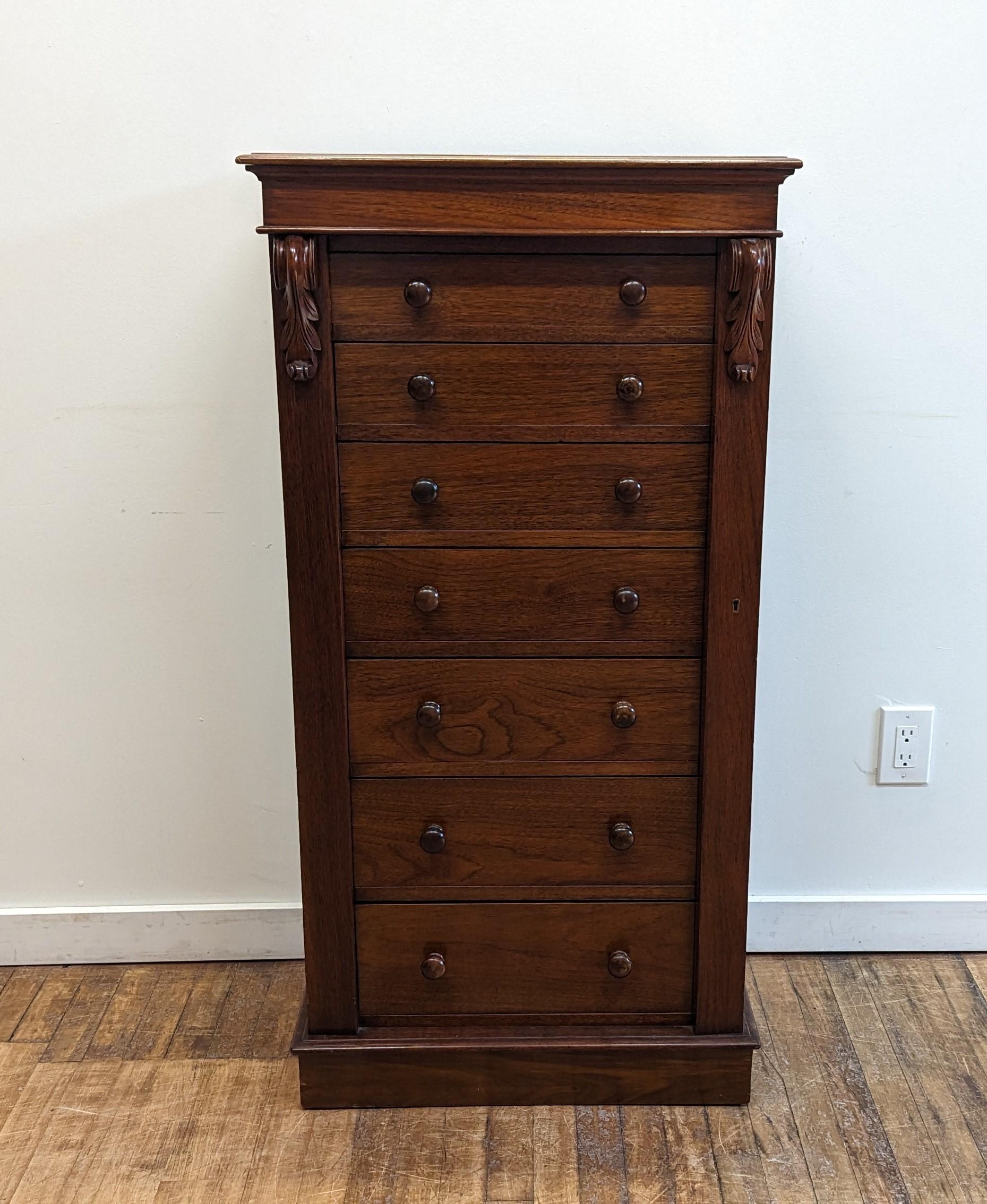 Antique Victorian Walnut & Mahogany Wellington chest of drawers, with seven graduated drawers and bun handles.  Locking bar on the right side keeps all seven drawers locked, has working key.  There are carved corbels on the top with a plinth base. 
