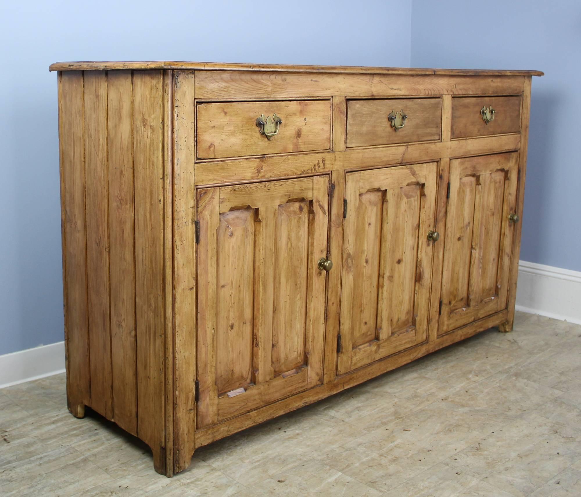 A pretty Welsh pine cupboard, sideboard or enfilade with rich patina and good honey color. Inset double panels on the doors add a nice design note. All of the three roomy drawers slide easily. The shelves in the three cupboards beneath are not