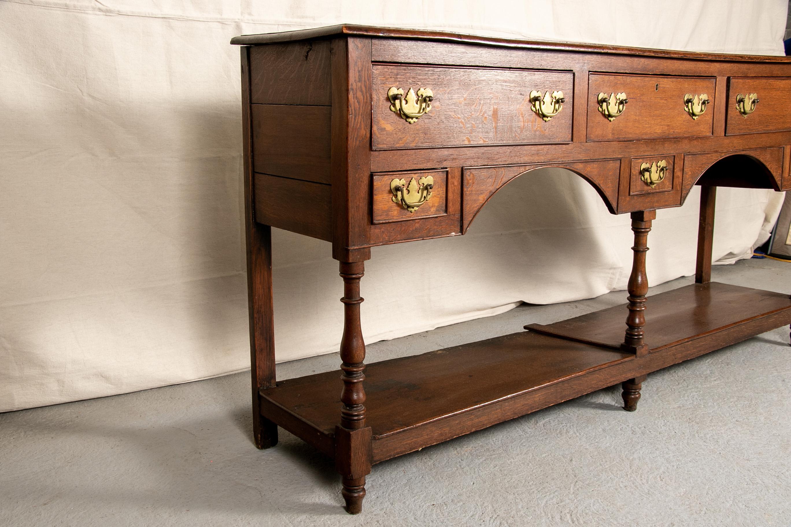 Welsh oak hunt board, narrow with a bull nose top edge, plank sides and three frieze drawers, the centre one with brass escutcheon (lacking the key) above a shaped front with small side drawers and a centre faux drawer. Raised on turned legs with a