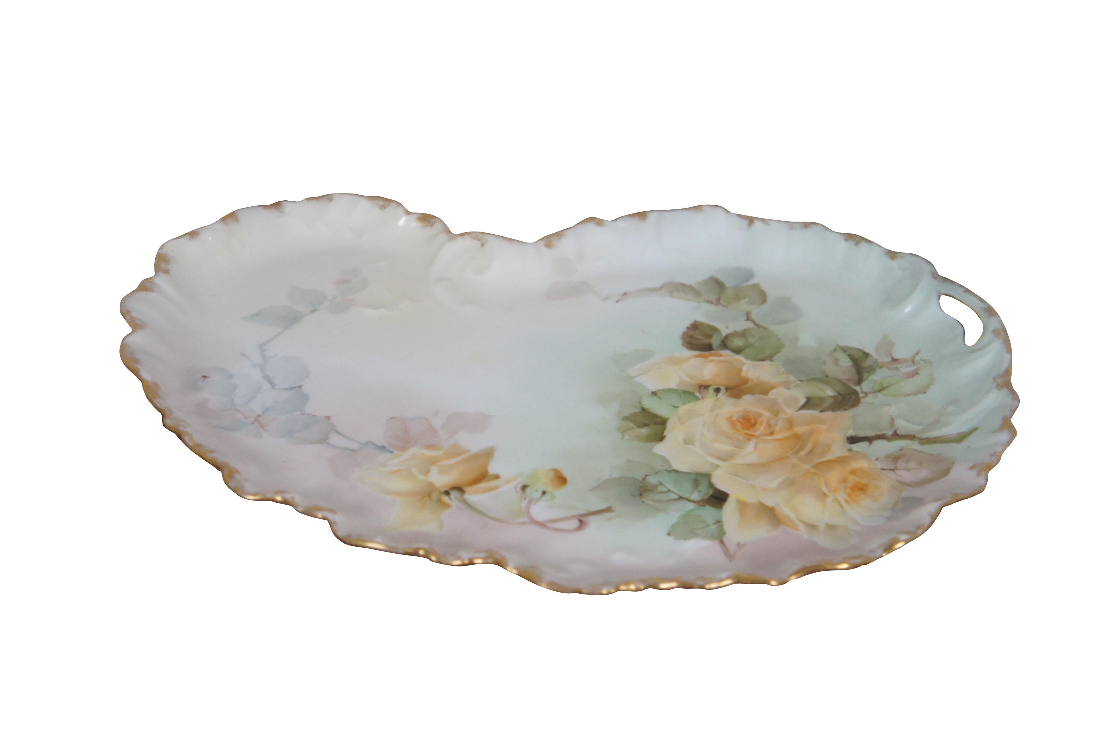 Late 19th - early 20th century Limoges porcelain vanity tray by William Guerin and Company. Kidney bean / artist palette shape with gilded, scalloped edge and pierced handle. Hand painted with green and mauve ombre and stems of yellow roses. Signed