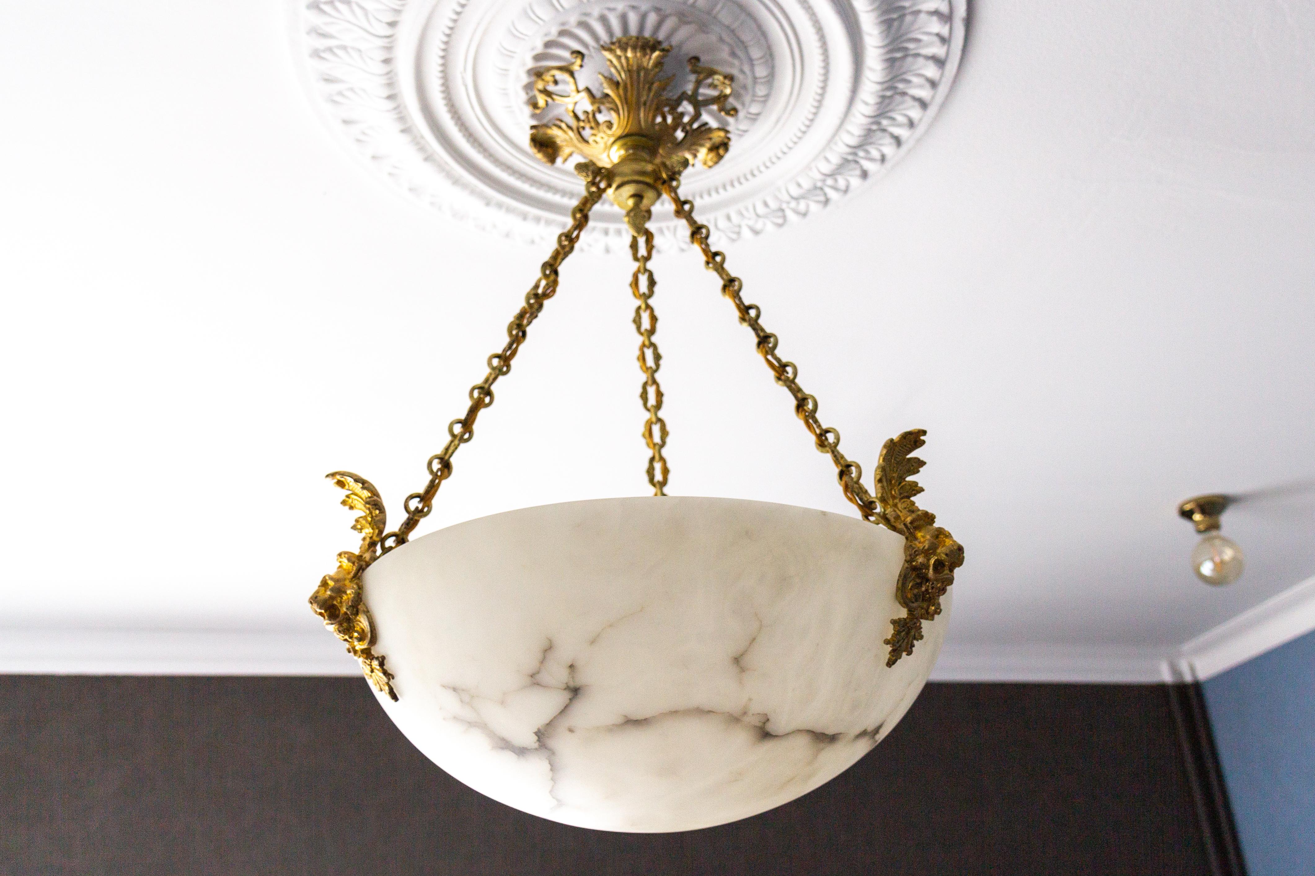 Antique and large three-light white alabaster and bronze pendant chandelier from circa 1900.
An impressive French pendant light featuring a white alabaster shade with gray and black veining. The elegant lampshade, a moon-like bowl is suspended from