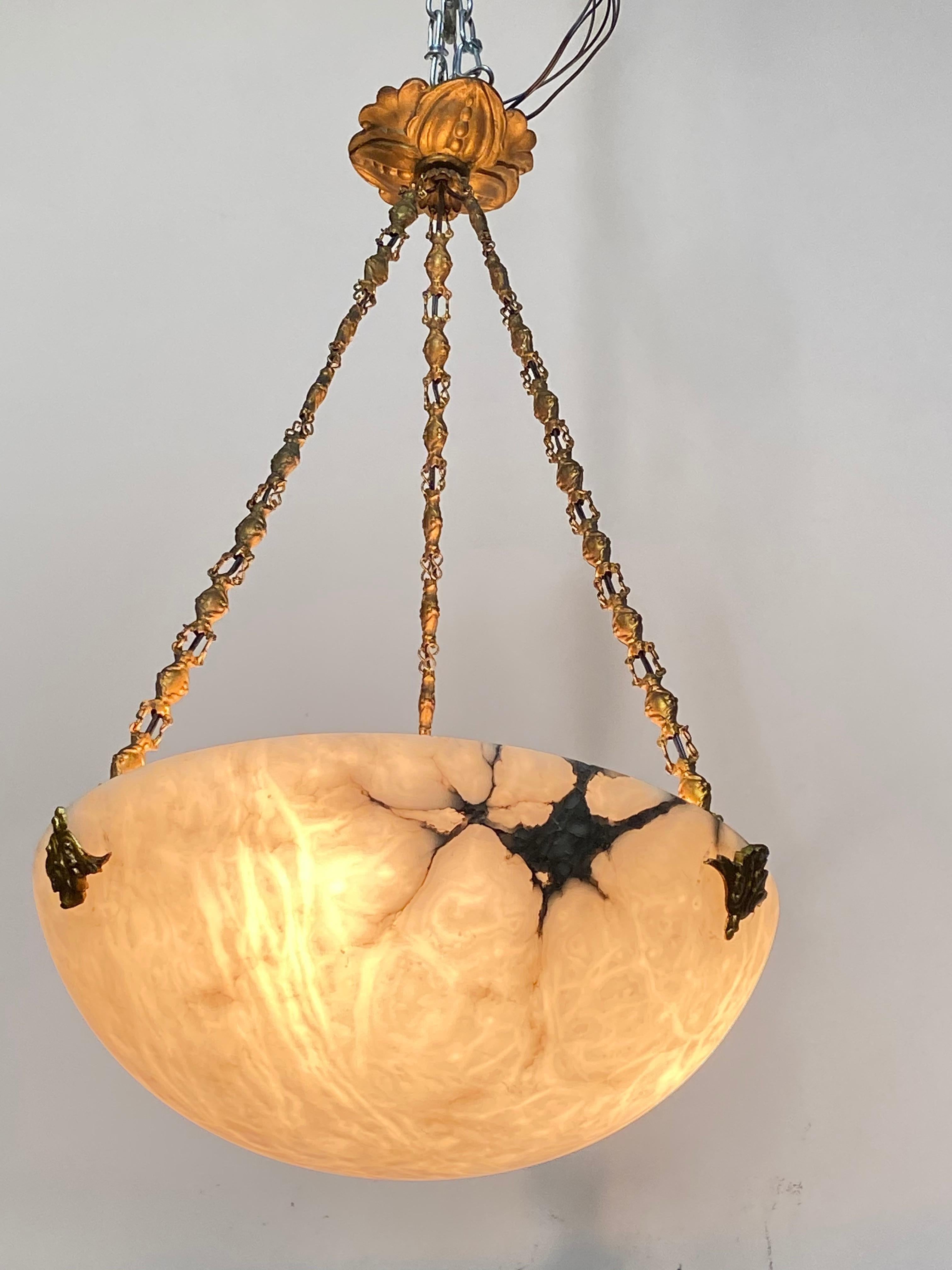 Antique white alabaster ceiling fixture with black and grey matrix and original brass chain hanger in very good condition. We can adjust the drop (overall height) on request for no extra charge. In the photos, the bowl appears amber-colored when