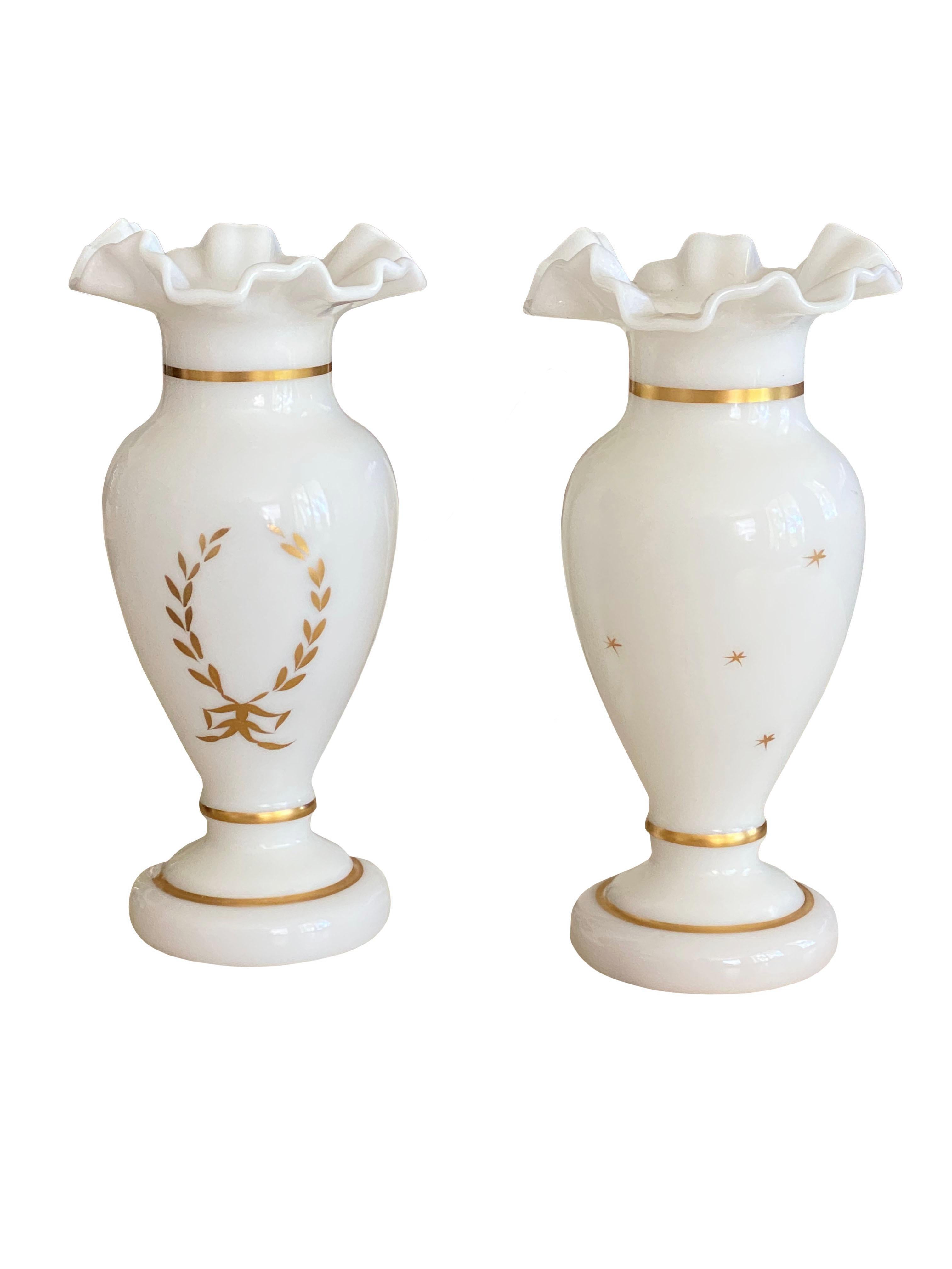A very pretty pair of antique white opaline vases with a ruffled rim. Hand painted gilt trim and laurel wreath with bow on front and scattered stars on back.