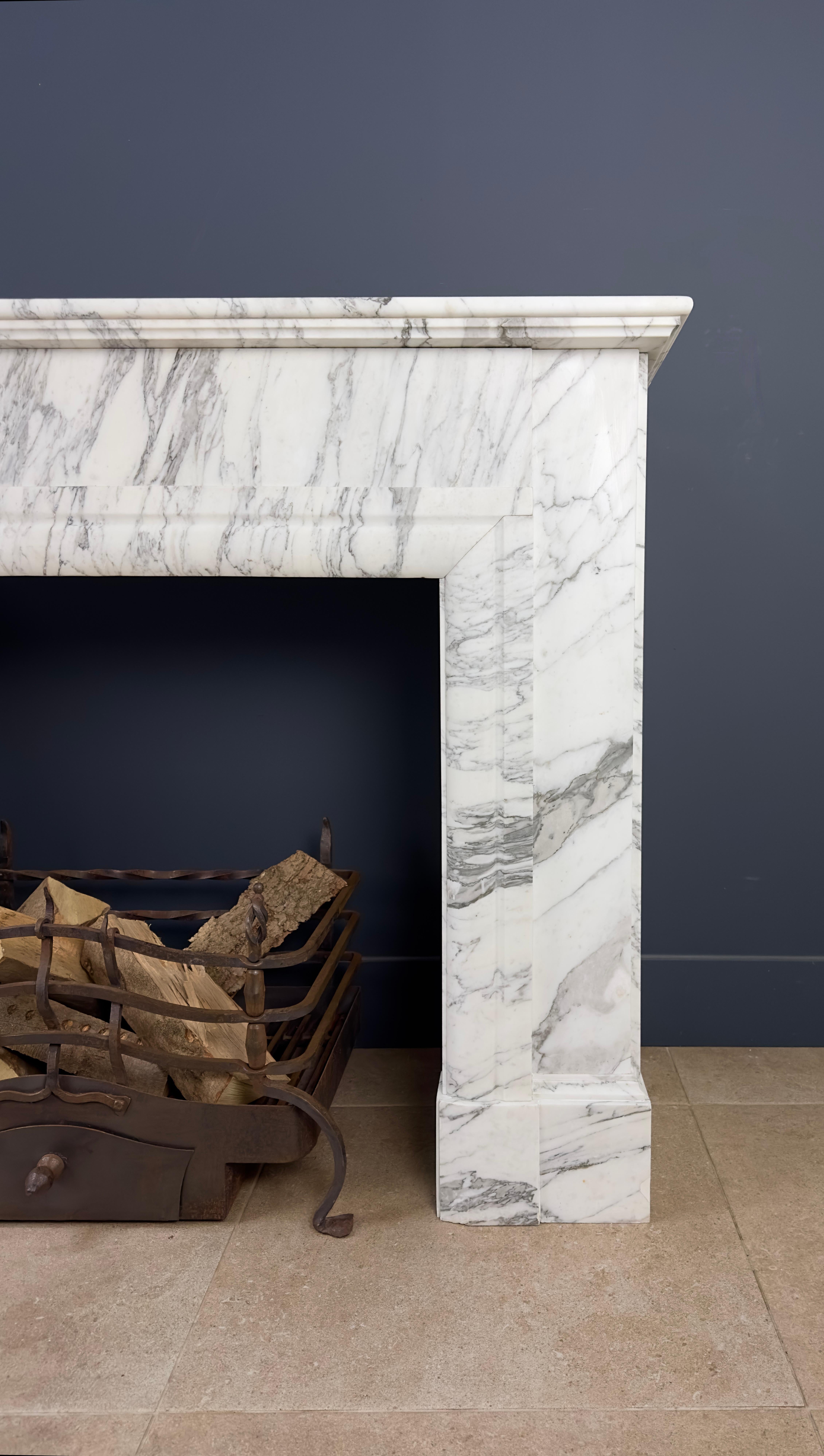 Entdecken Sie diesen schönen antiken Art Deco-Kamin aus Carrara-Marmor, dessen Adern seine natürliche Pracht noch unterstreichen. Dieser Kamin verkörpert eine Verschmelzung von Eleganz und Opulenz, was ihn zu einem zeitlosen Möbelstück macht, das