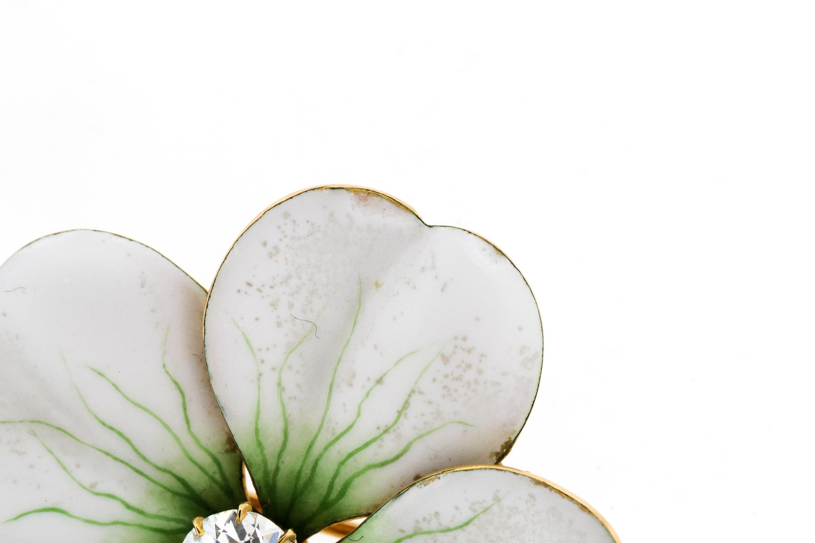 Antique Art Nouveau 18k gold white enamel flower pin set with an Old European cut diamond, circa 1900. The bold white petals has green enamel details creating the realistic quality of the flower. There is a small gold stem at the bottom of the