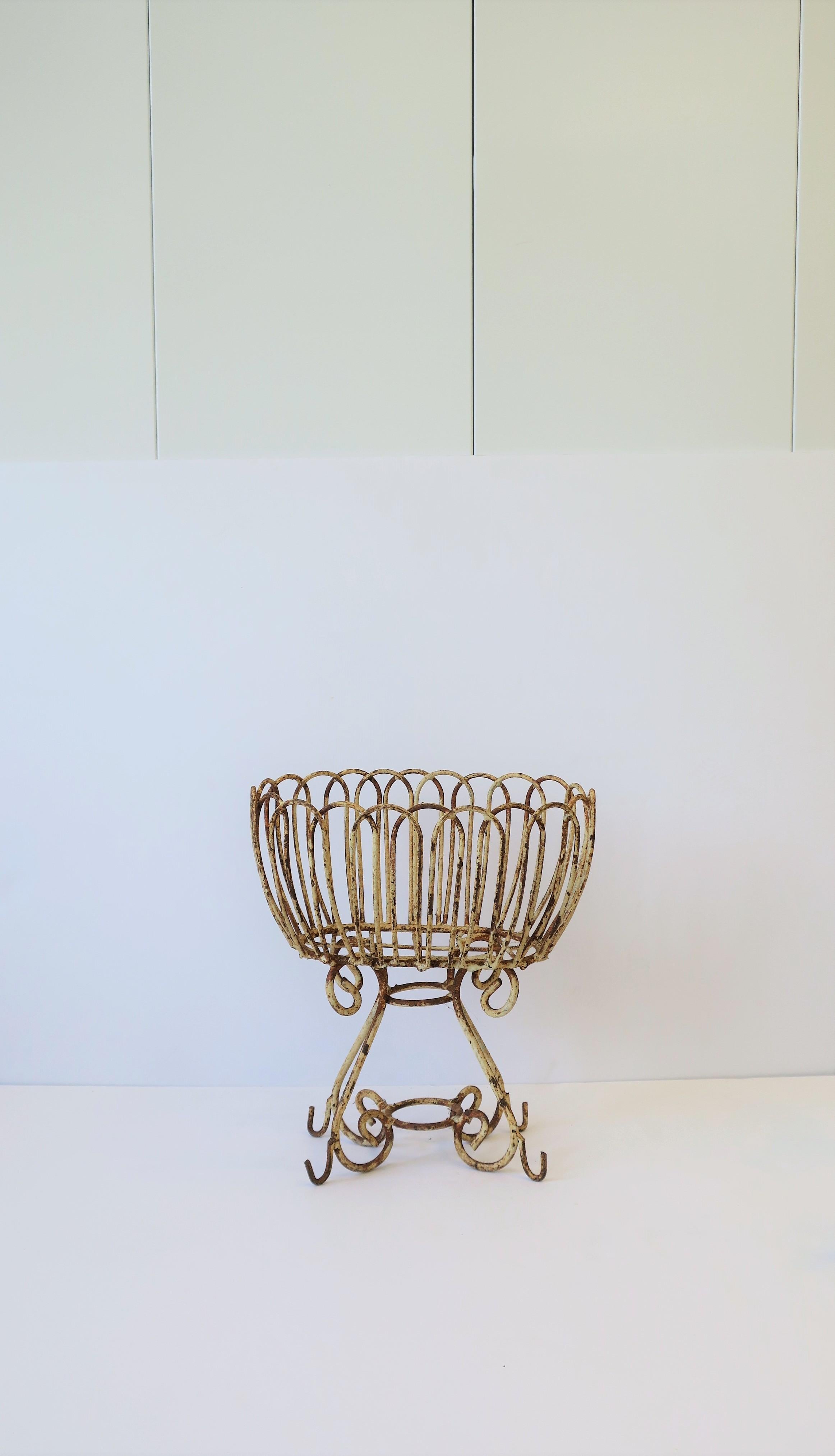A beautiful antique white garden or patio planter jardinière, circa early 20th century, France. Iron metal wire frame is beautifully designed and decorated with loop and scroll details. Piece can be used indoors or outdoors. Piece is shown with an
