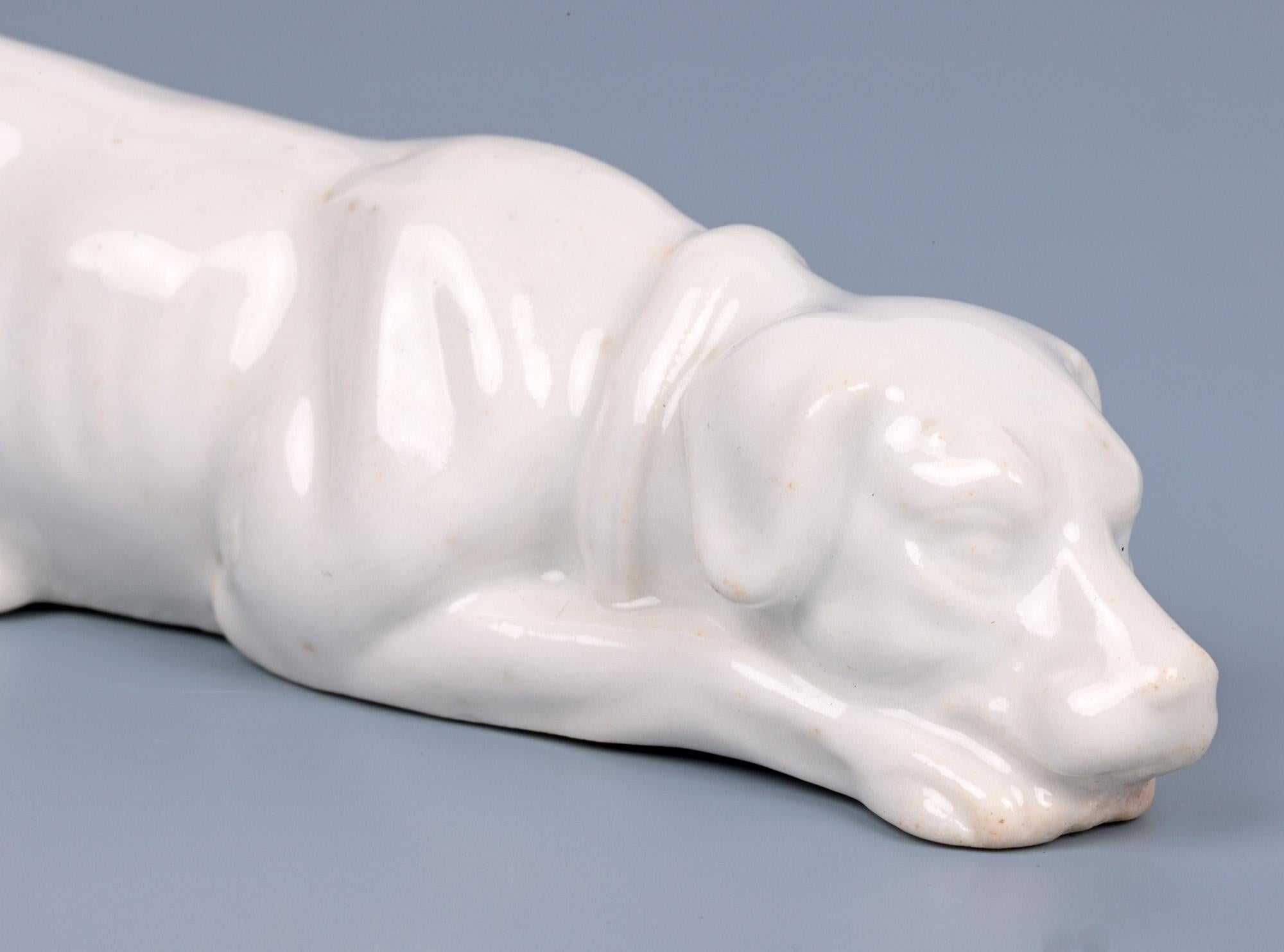 An exceptional antique, probably English, white glazed porcelain figure of a recumbent hound dating from the early 19th century. The figure is finely hand crafted with wonderful detail with the hound resting its head on its outstretched front paws