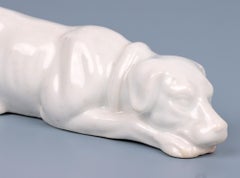 Antica figura di cane da caccia supino in porcellana smaltata bianca