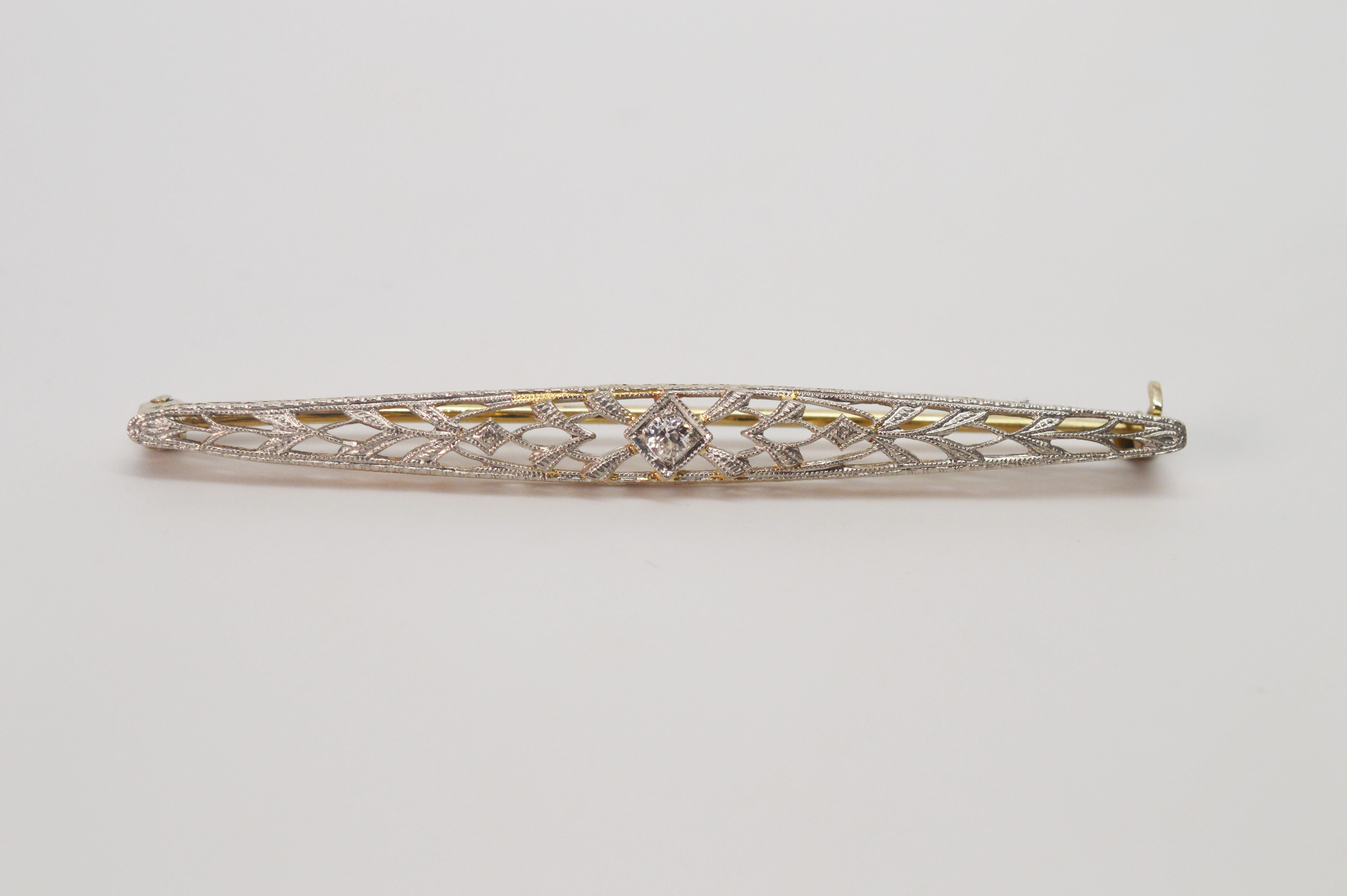 Antique diamond-cut ten carat white gold filigree bar pin with .05 carat diamond accent. Oblong, measures 2-1/4 inches long and approximately 1/4 inch wide at center. 