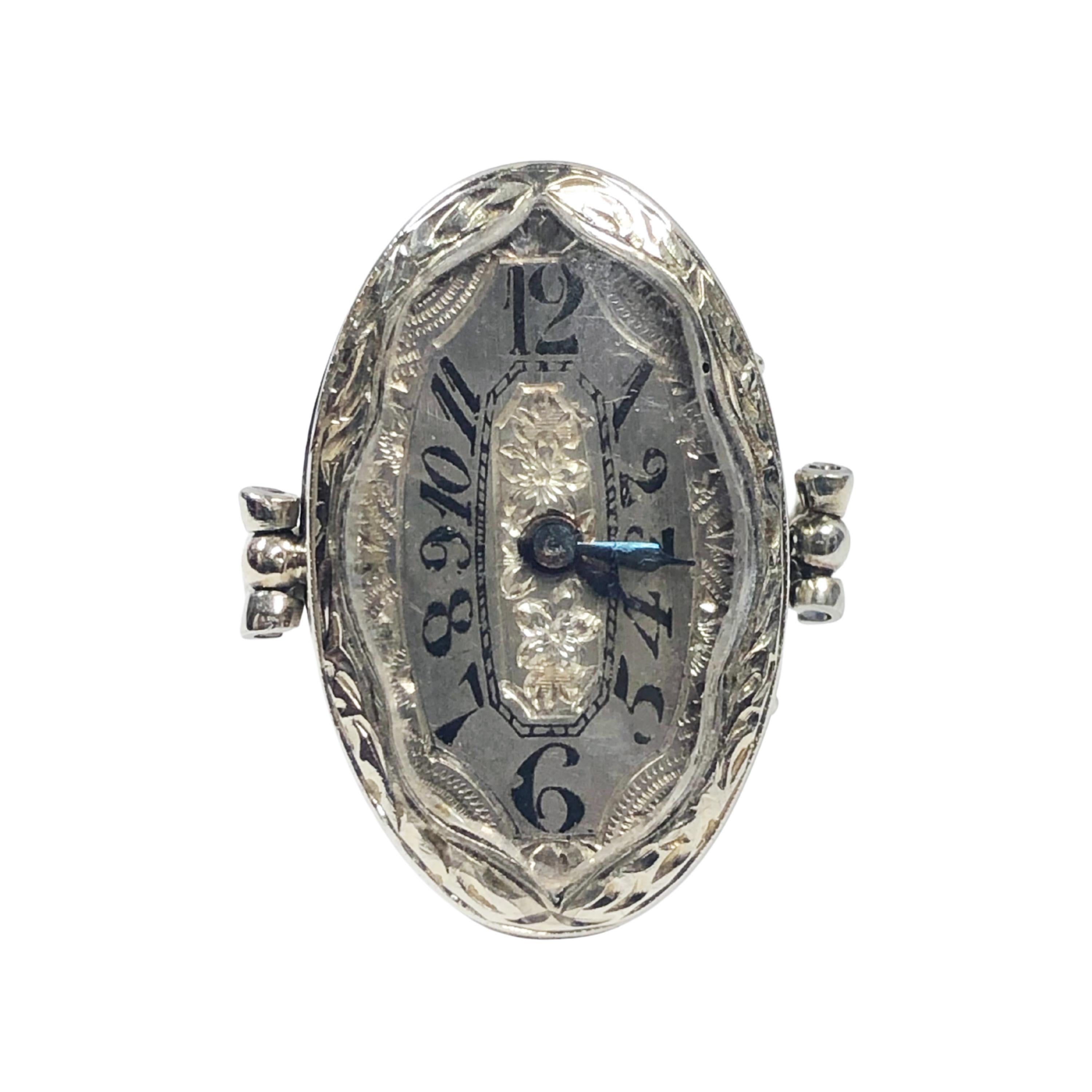Circa 1920s Ring Watch, 14k White Gold with hand engraved design work, the oval top measures 7/8 X 9/16 inch. 17 jewel Fortis Mechanical, manual wind movement. silver dial with Black numerals and hand engraved design work. The watch is wound by a