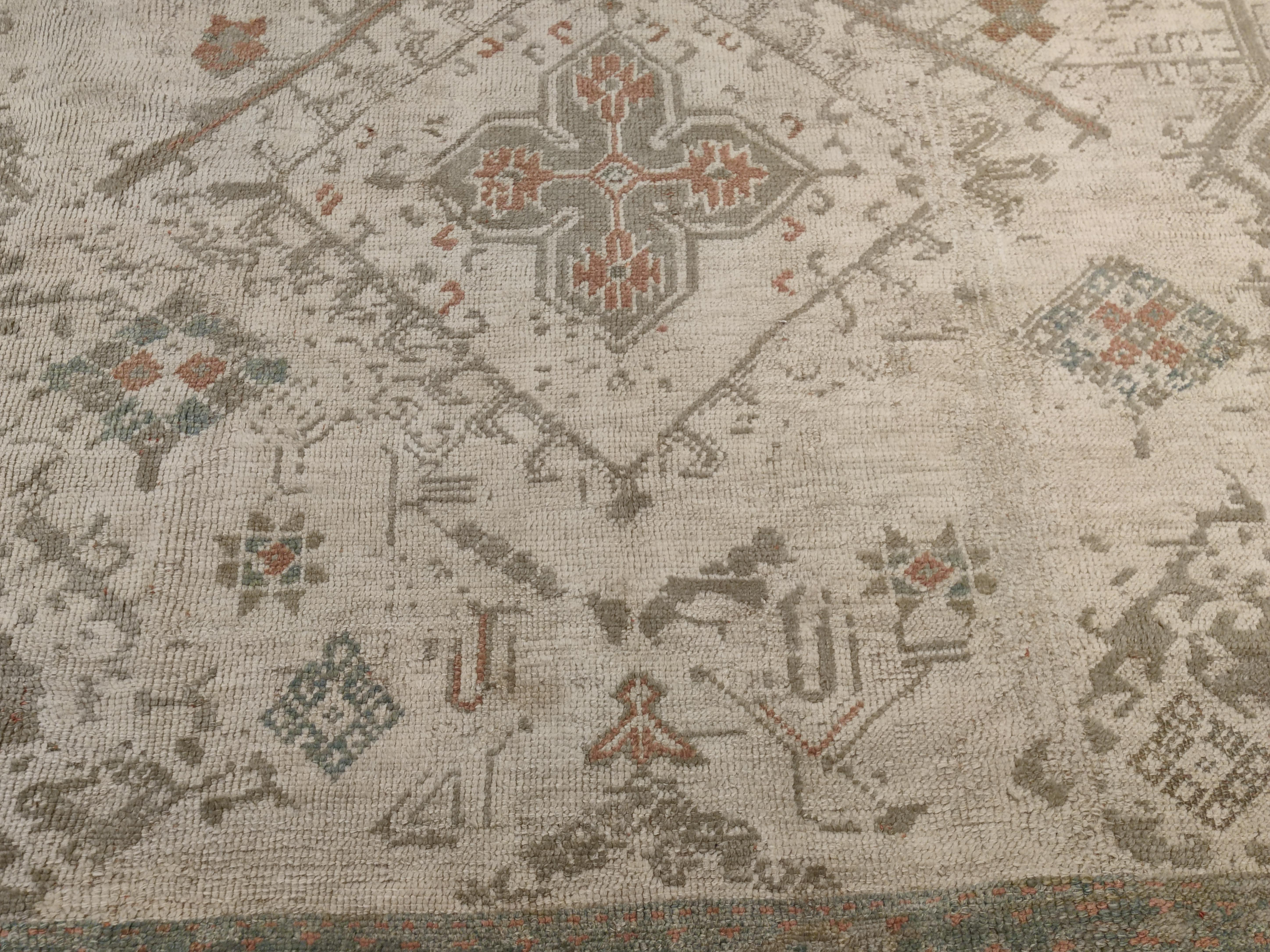 Ein raffinierter und eleganter Oushak-Teppich in Übergröße, der sich durch ein großflächiges Muster aus parallelen und versetzten Reihen von vierzackigen Sternen auszeichnet, die für Oushak-Teppiche aus dem 16. Die weiche Farbpalette besteht aus