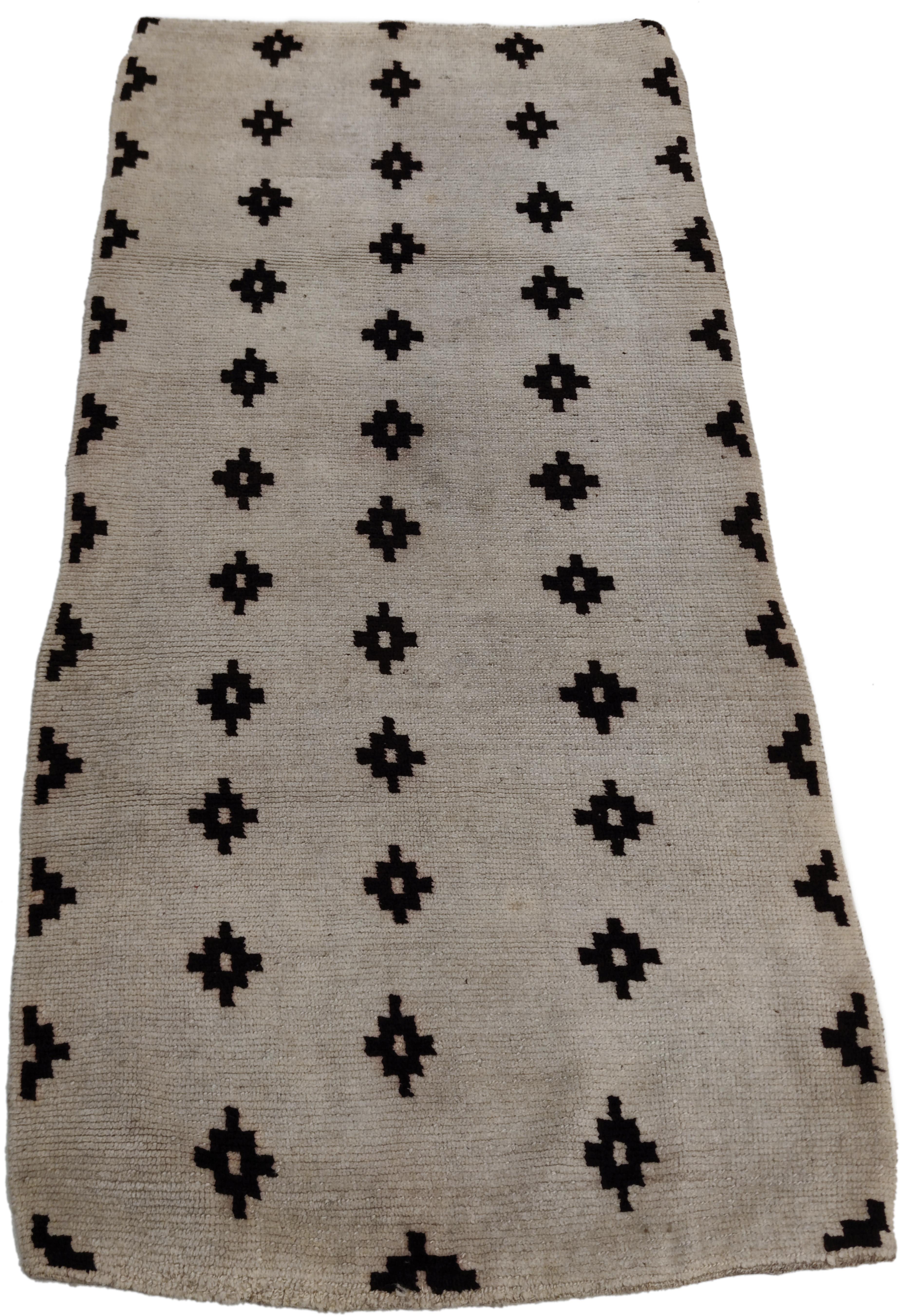 Un rare et élégant tapis tibétain au format khaden qui se distingue par un fond blanc comme la neige décoré par une répétition infinie de rangées parallèles et décalées de diamants noirs étagés, créant une composition chromatiquement équilibrée. Les