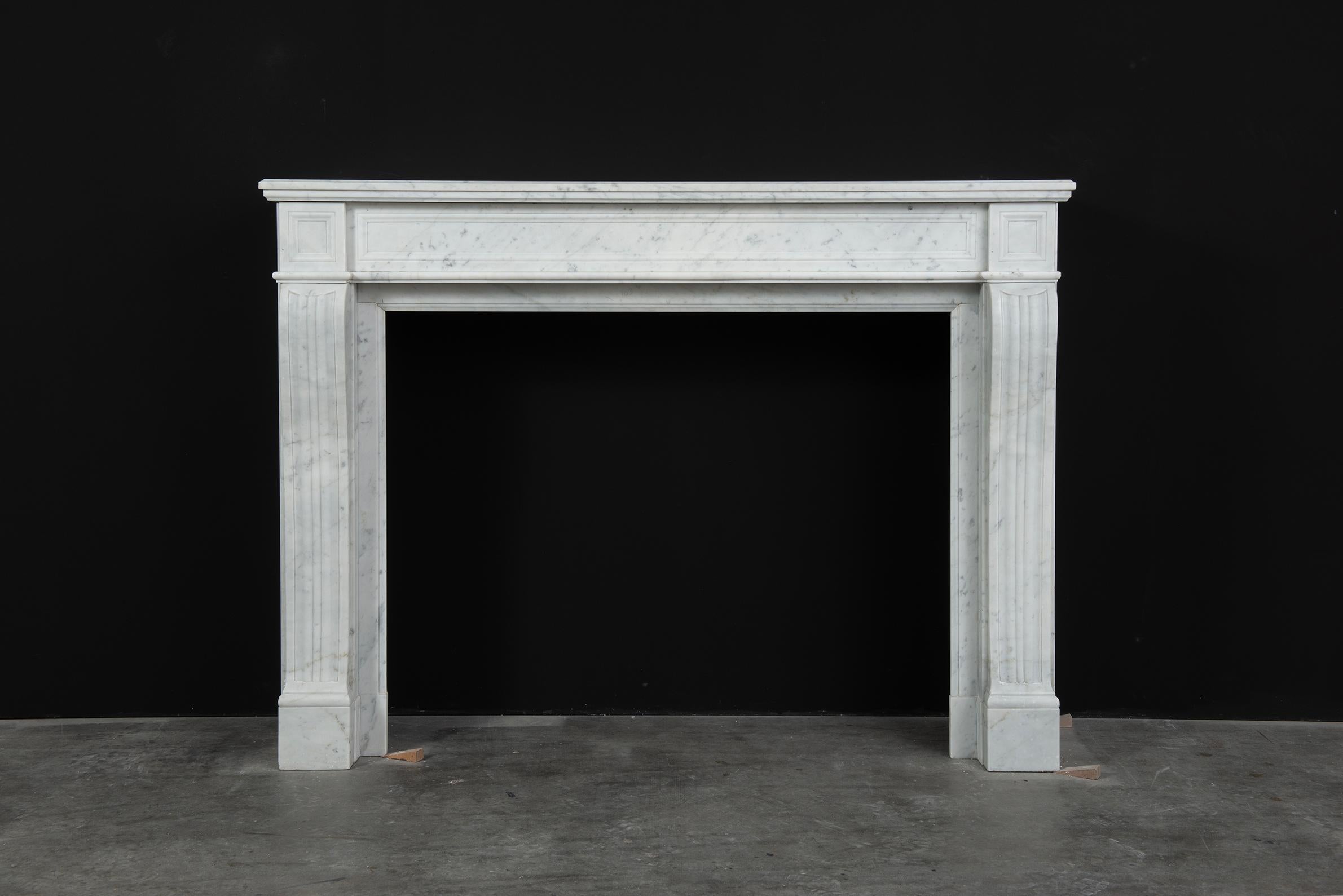 Antique White Marble Louis XVI Fireplace Mantel.

Lovely simple and elegant white marble Louis XVI fireplace mantel.
The rectangular and profiled top shelf rest on a simple paneled straight frieze with endblocks on both sides that have the same