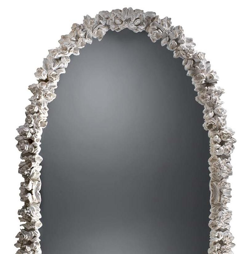 Set inside an antique white frame decorated with a closely knit bouquet of hand-carved flowers, this oval mirror is the perfect accent in a romantic bedroom or over a traditional-style entryway console. The Baroque inspiration of the exquisitely