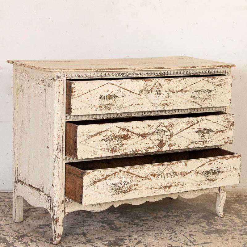 The repeated carved diamond motif is captivating in this chest of three drawers from France. The newer white paint adds a touch of grace while the distressing reveals the natural oak beneath. The scalloped skirt and cabriolet feet add a touch of