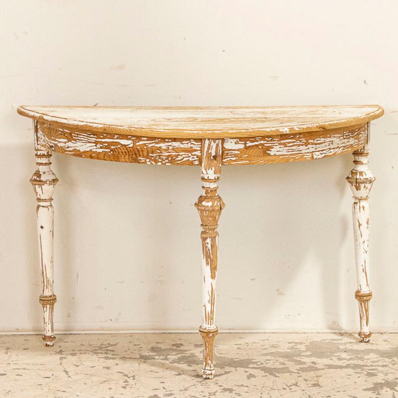 While most of the original white paint has been scraped off, it is this very distressed feel that give this demilune table such a warm and comfortable 