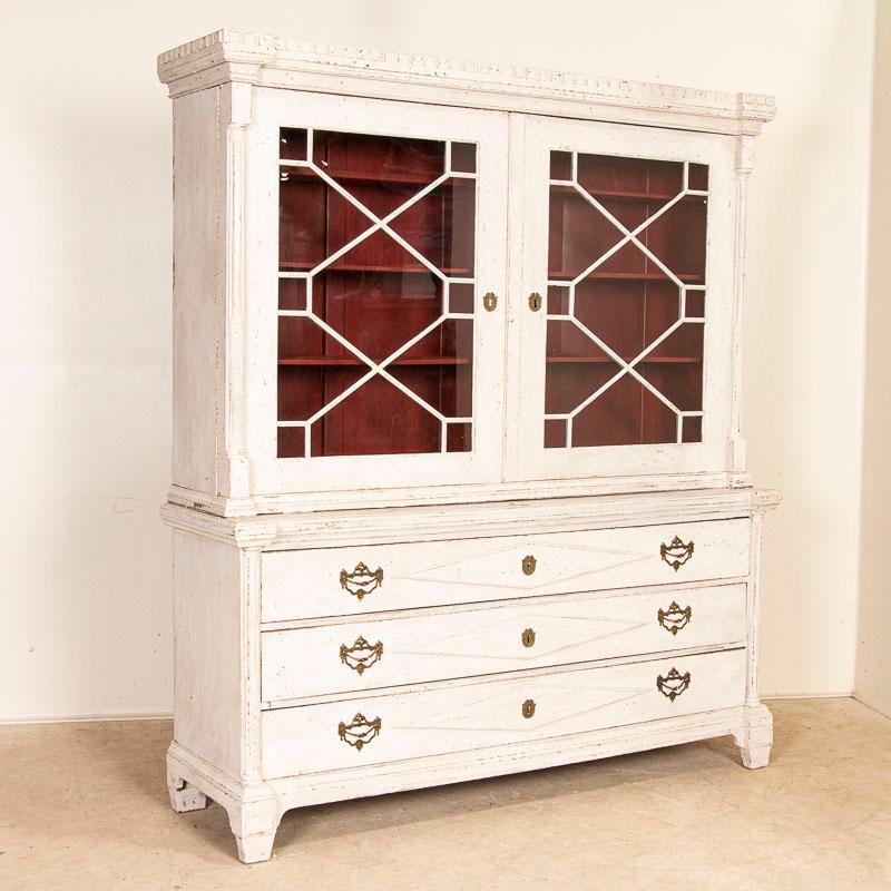 This lovely gustavian display cabinet is an exceptional find due to the rare size at just over 6' wide. Notice the extended/carved diamond motif on the long drawers with 2 large brass pulls on each. The decorative trim on the glass doors and dentil