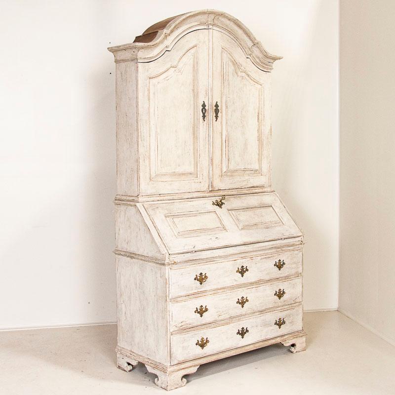 Stately and elegant, this tall white gustavian pine secretary shows off with the distinctive shape of the top bonnet or crown. Also known as a bureau, this secretary would have been a 