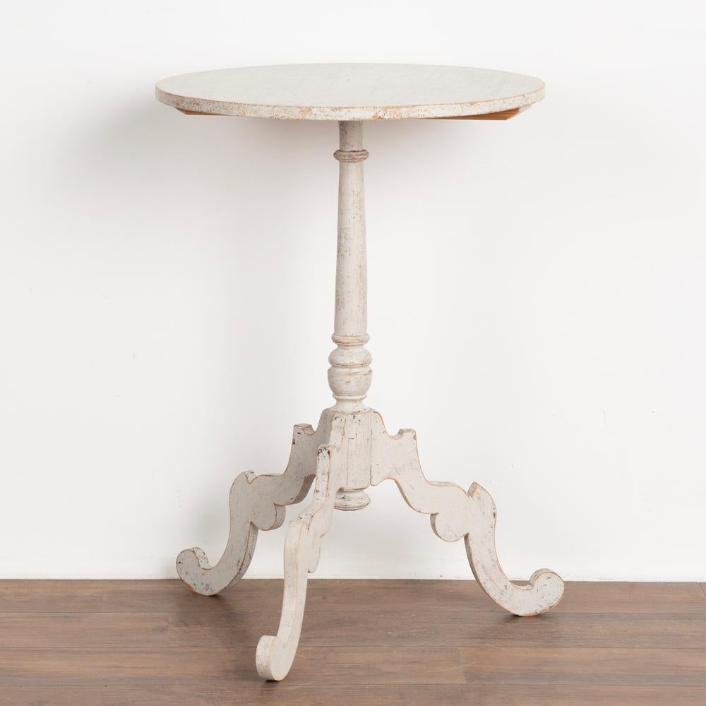 Antique Swedish gustavian tri-foot turned pedestal side table.
Later applied professional white painted layered finish, lightly distressed to fit the age and grace of this Swedish country table.
This side table may also be used as a nightstand,