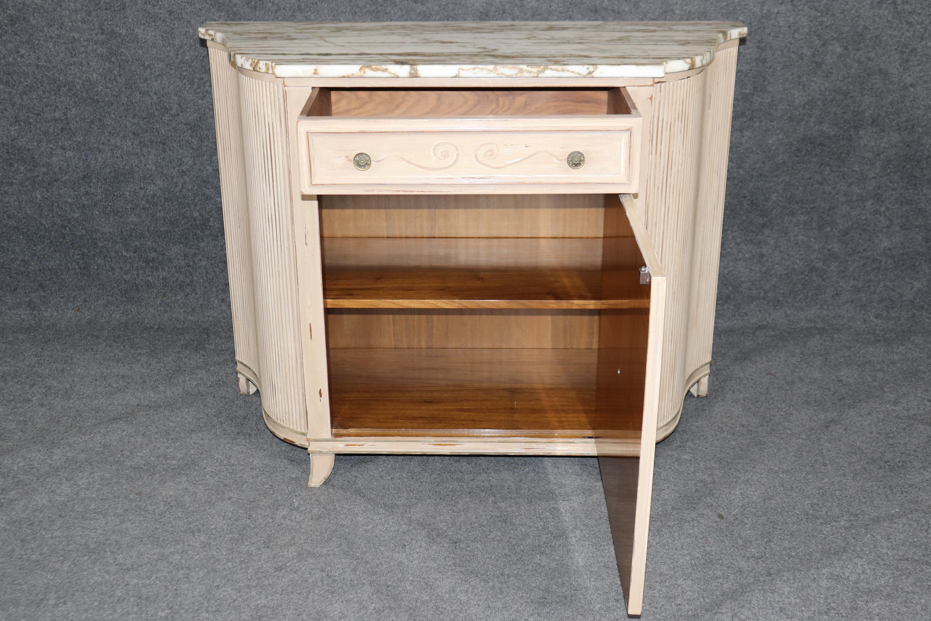 Il s'agit d'une commode unique et sophistiquée peinte en blanc antique avec une seule porte et un seul tiroir avec un magnifique plateau en marbre blanc et veines d'or crème. La commode est en bon état et présente des signes normaux d'usure et