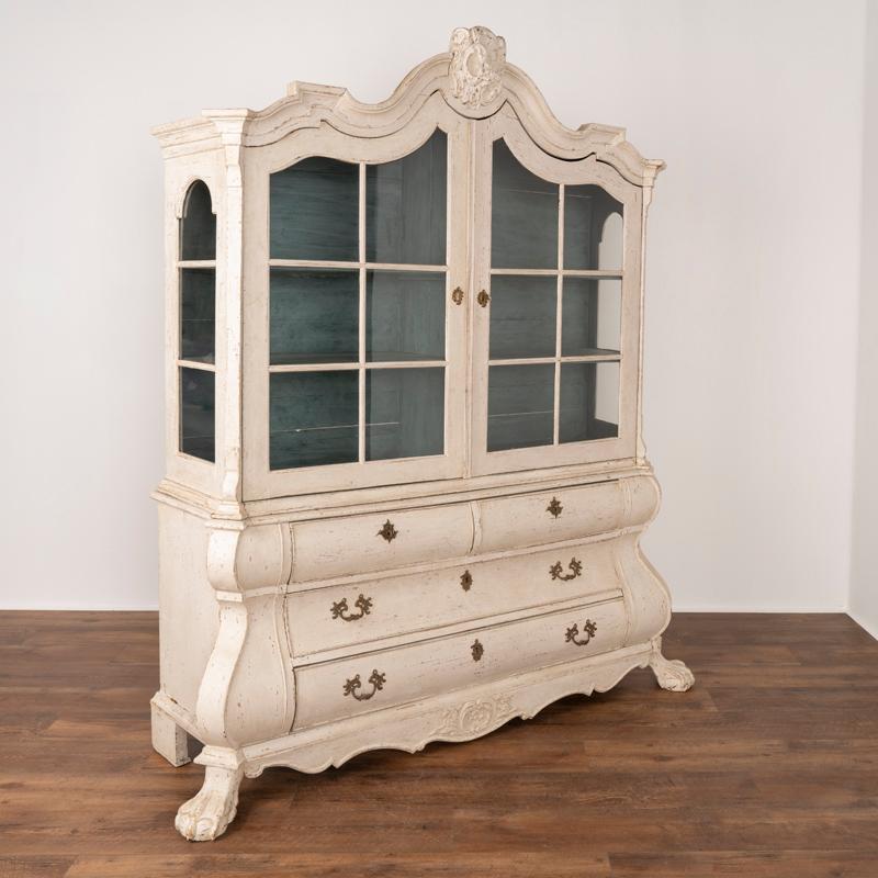 Lovely rococo curves and carvings accentuate this striking Vitrine or display cabinet from Sweden. Note the exagerated curves and heavily carved feet that combine for dramatic effect. The newer, professionally applied white painted layered finish