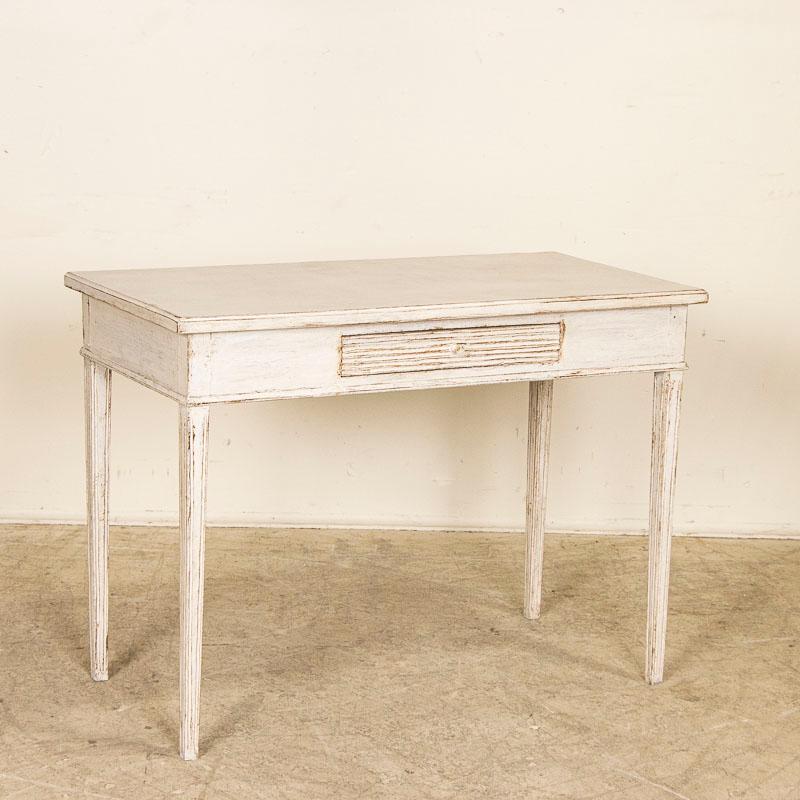 The perfect patina in the (newer professionally applied) white painted finish gently graces this delightful side table from Sweden. Notice the single drawer with hand-carved grooves, a traditional Swedish style element along with the tapered legs