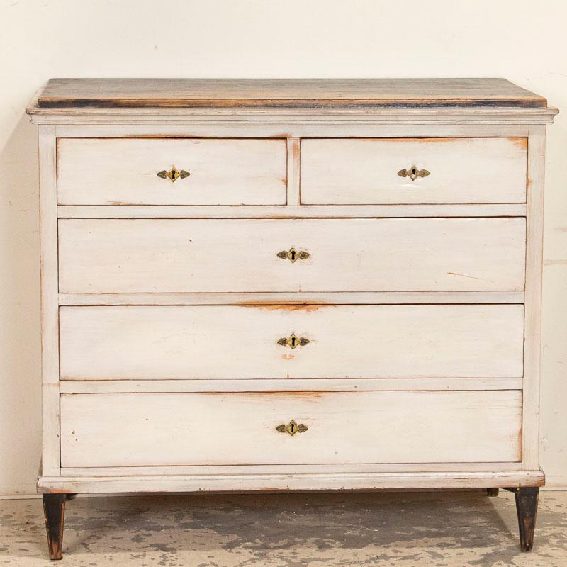 The lovely clean lines of this antique chest of drawers fit the simple and appealing Swedish gustavian look of the dresser. The gently distressed white paint has been worn down to the natural wood where the drawers were most often touched. The white