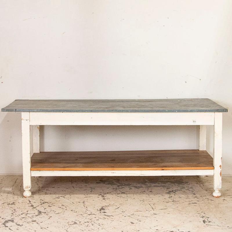 What a fun find! This vintage farm table has the original zinc top and a lower shelf, indicating it was used as a type of work table in its former life. The zinc, which has great aged patina, wraps around 3 of the four sides; as seen in the photos,