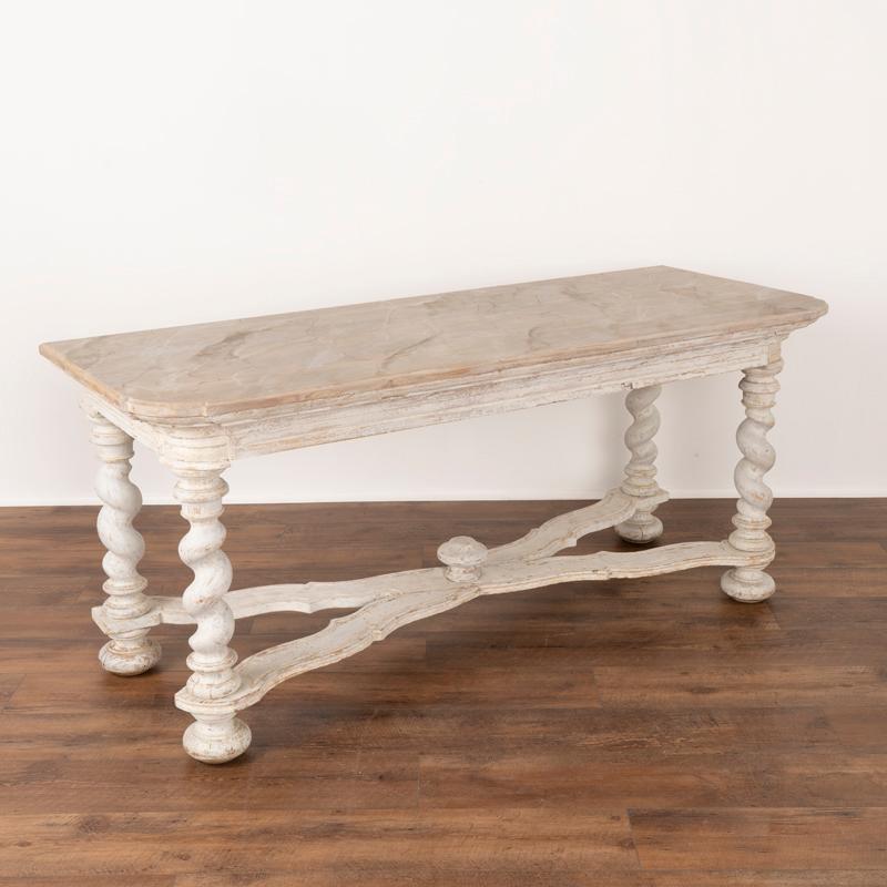 This lovely antique revival writing table will serve well as a large console table in today's home. The newer applied professional white painted finish shows off the X shaped stretcher and impressive barley twist legs. Examine the close up photos to