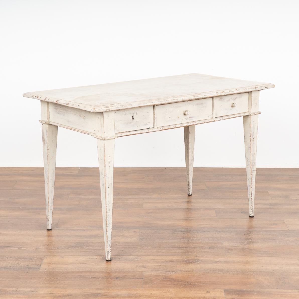 Swedish country pine side table with three drawers standing on four tapered legs; may also serve as an informal writing table or desk.
Drawers function; unique to this table is the center and right drawers have a wood pull, while the left drawer