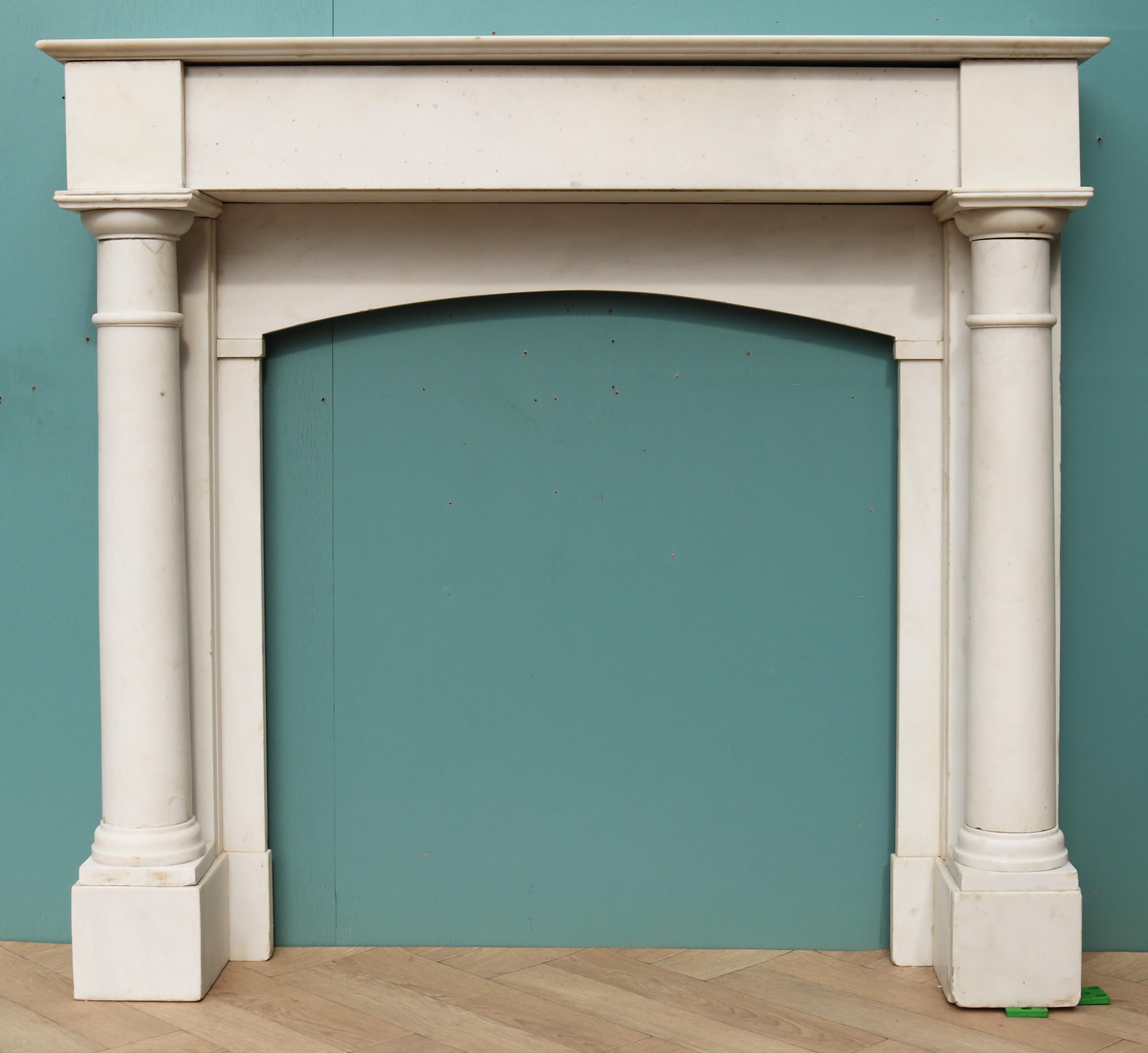 A compact antique white statuary marble fire mantel with full column supports dating from the mid 19th century. Crafted from fine quality statuary marble, this antique fireplace showcases influences of classical Louis styling with impressive