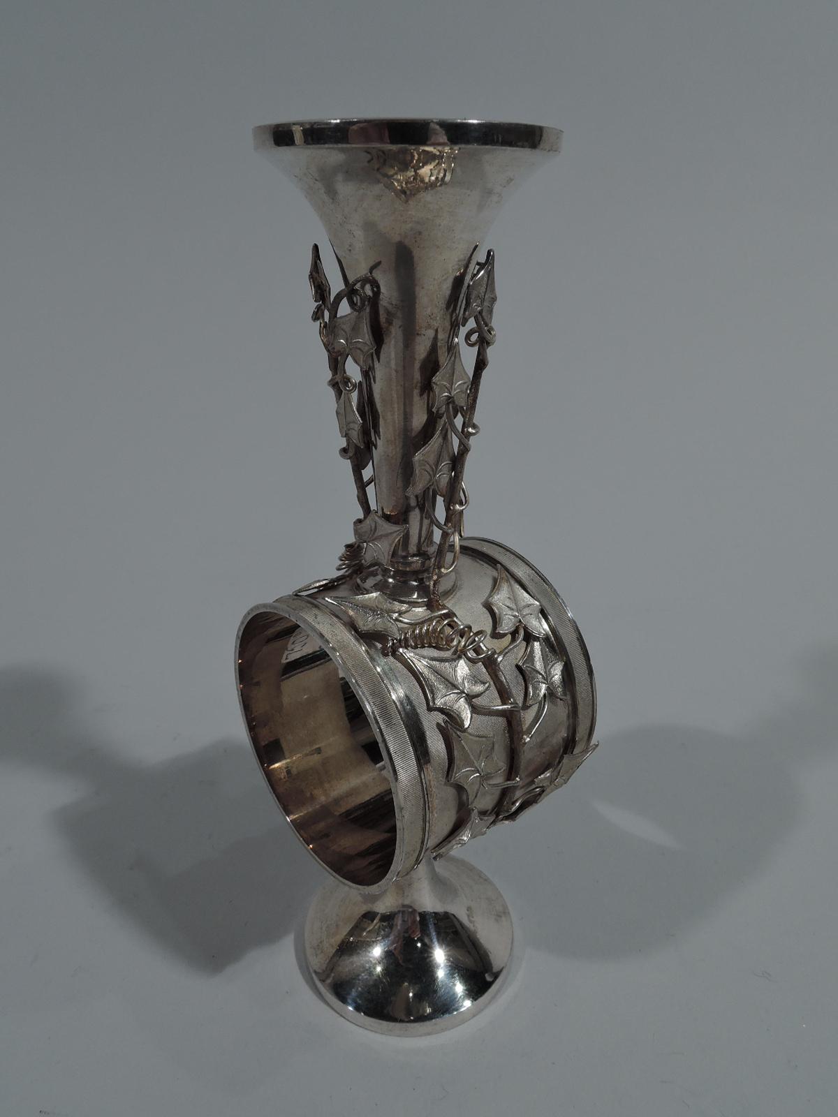 Aesthetic sterling silver napkin ring. Made by Whiting in New York, circa 1885. Conical bud vase mounted to ring, in turn, mounted to raised and plain foot. Ring finely ribbed with applied ivy vine that climbs up vase sides. Fully marked and
