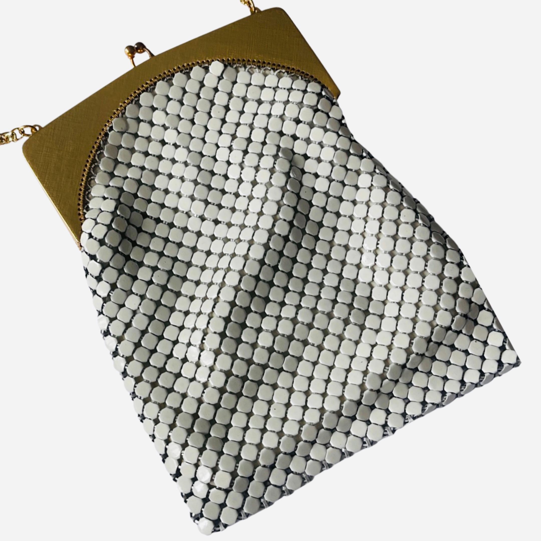 An ornate, rare piece of history is this Whiting & Davis mesh purse, Circa. The 1920s-1929.  This white-in-color antique chainmail purse is framed in gold with a decorative frame that has a figural face, along with leaves and roses.  

The gold