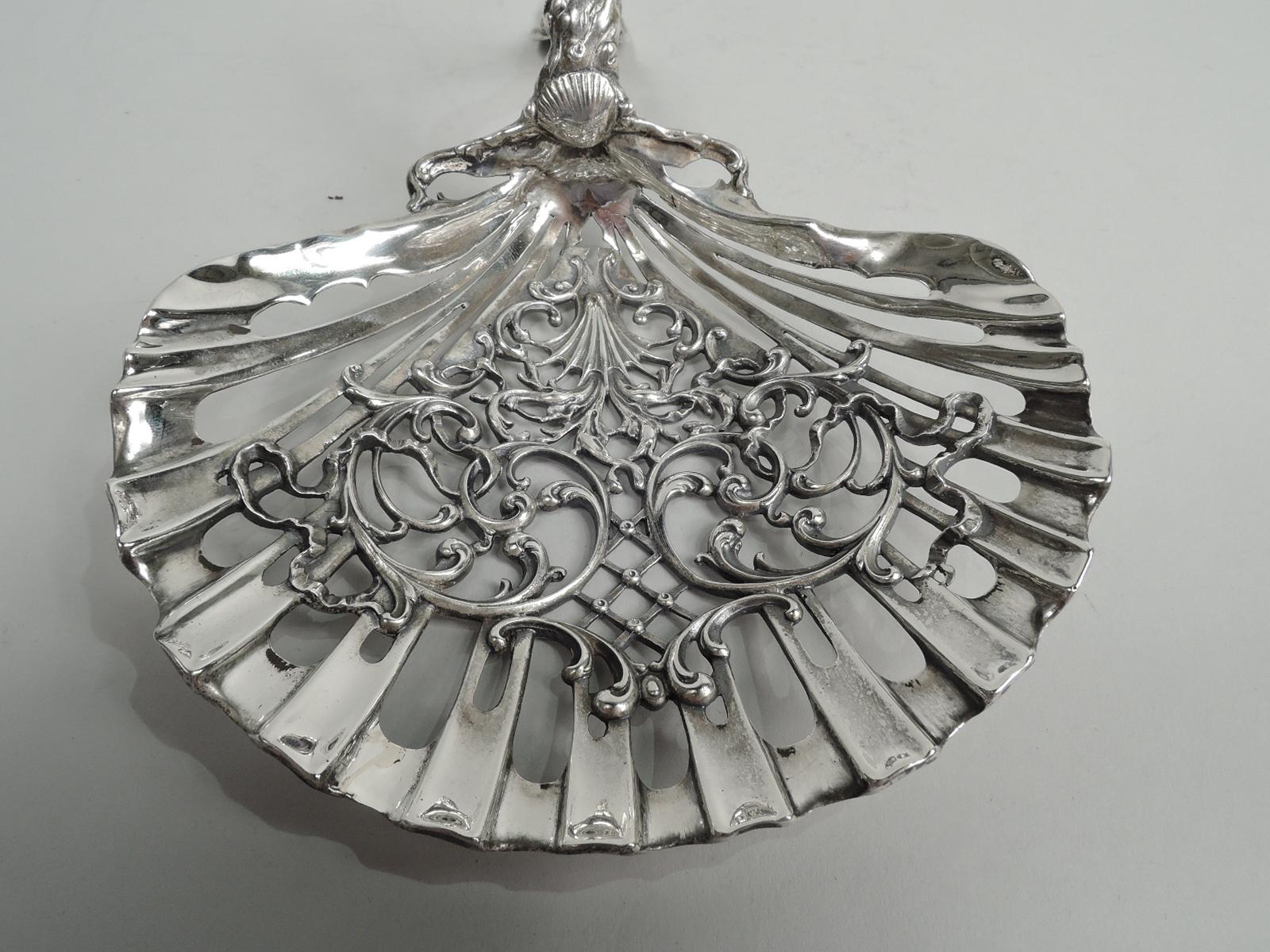 Turn-of-the-century Edwardian Art Nouveau sterling silver bonbon scoop. Scallop shell bowl with open flutes inset with open scrolls and diaper. Scroll handle comprising seaweed-entwined shells. A great piece for the weekend cottage. Fully marked