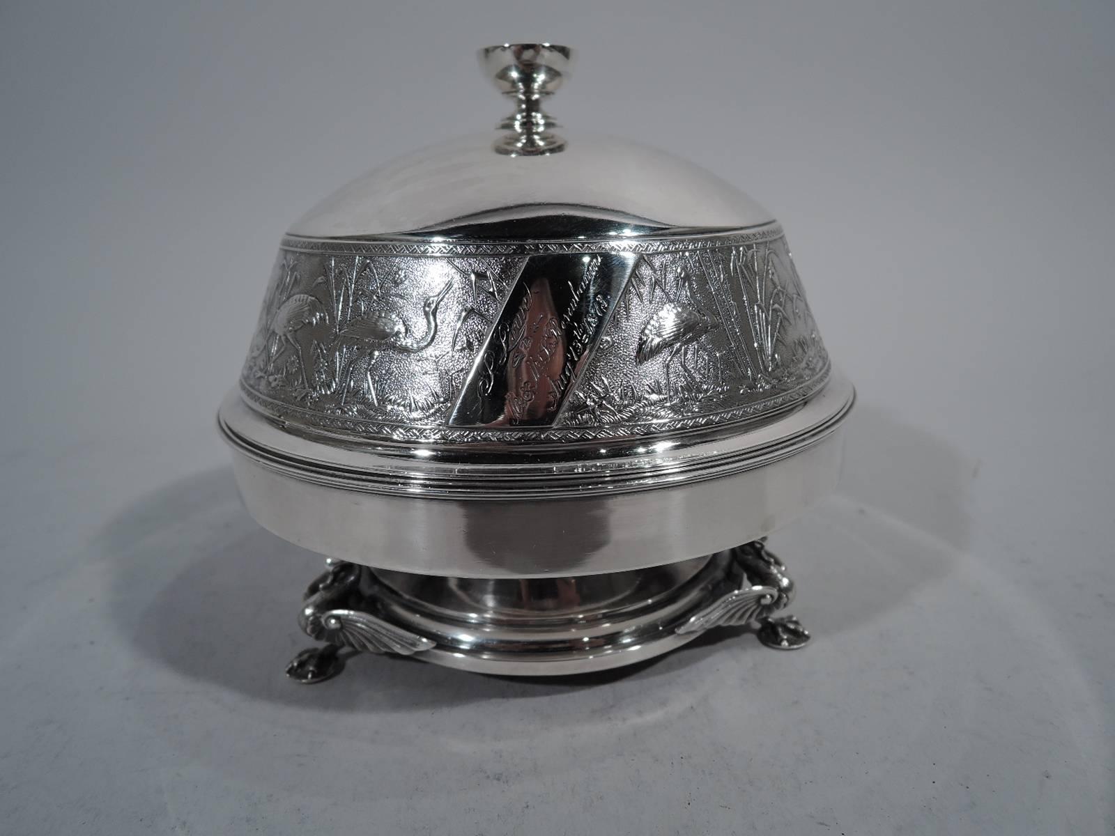 Japonesque sterling silver butter dish. Made by Whiting in New York. Shallow bowl on stepped foot supported by three monopodia bird supports with outstretched wings. Cover domed with plain top and footed cup finial. Low-relief frieze on stippled