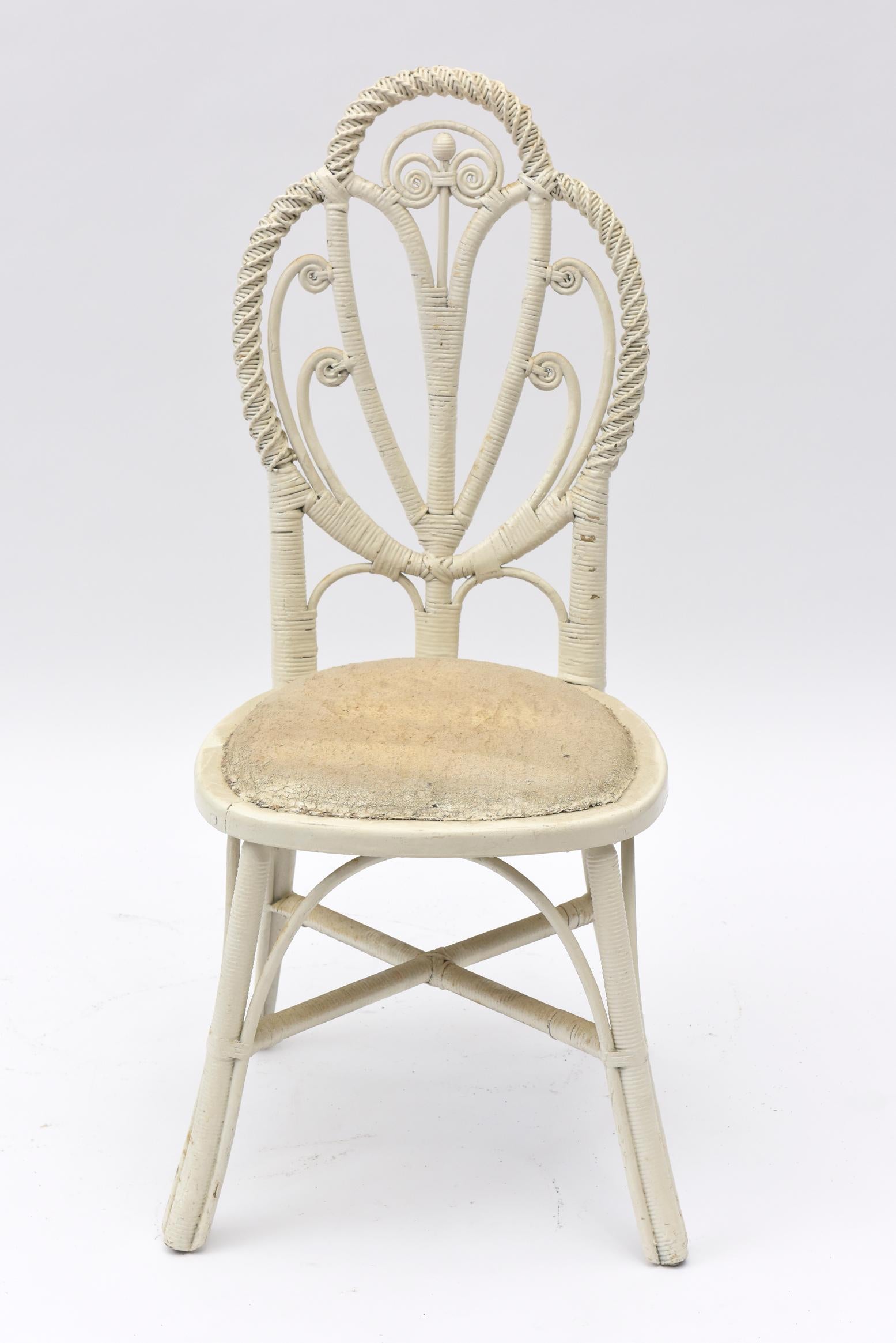 Late 19th century wicker chair has a 3 interlocking woven twisted inverted pear shapes to form its back. Inside the pears are curlicues topped with a single centre bead. It has simple legs and an upholstered cushion seat. It would be a sweet chair