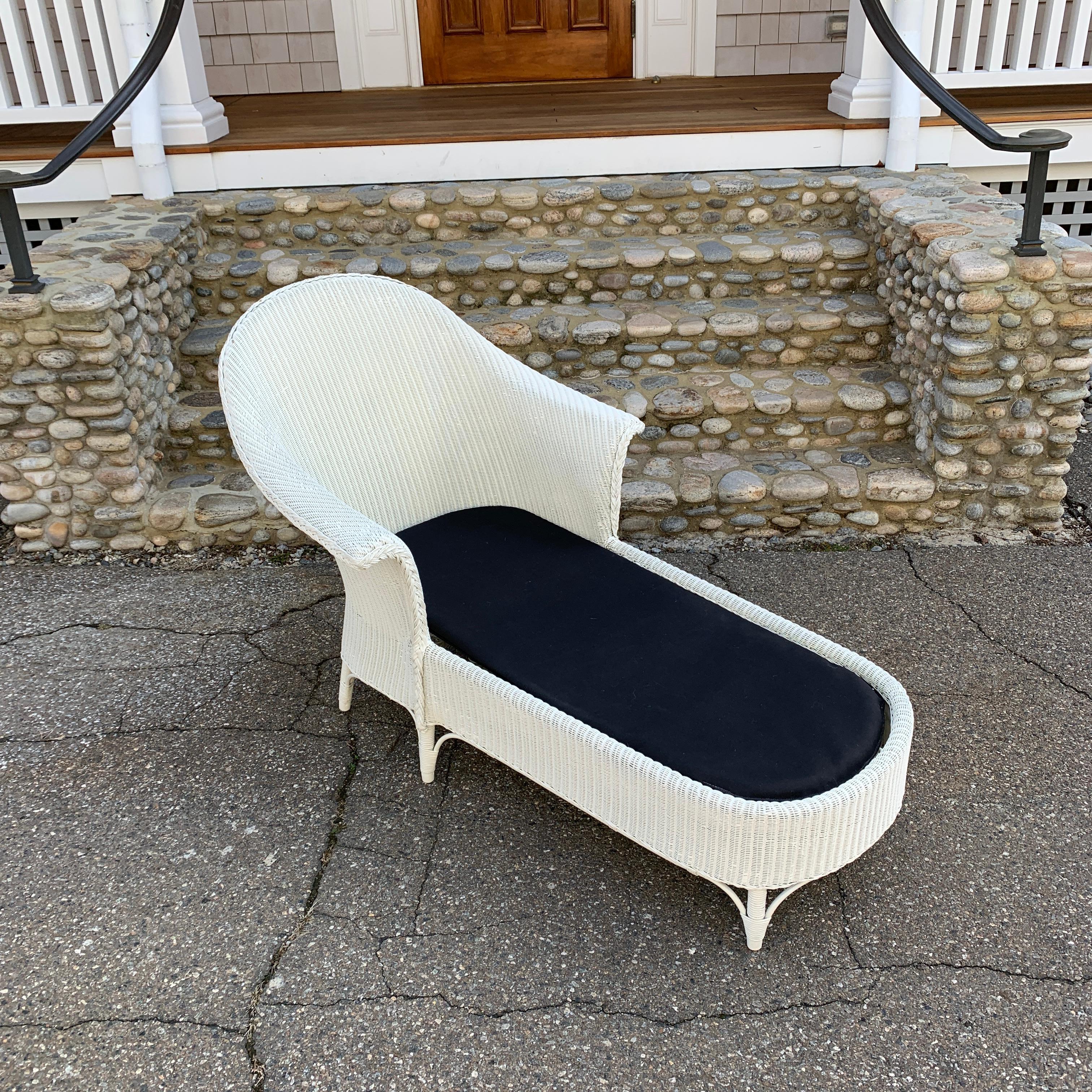 Antique Lloyd loom wicker chaise in white paint. Fabric decking covers a spring platform. Paint has blended in some areas but piece is sound, sturdy and comfortable.