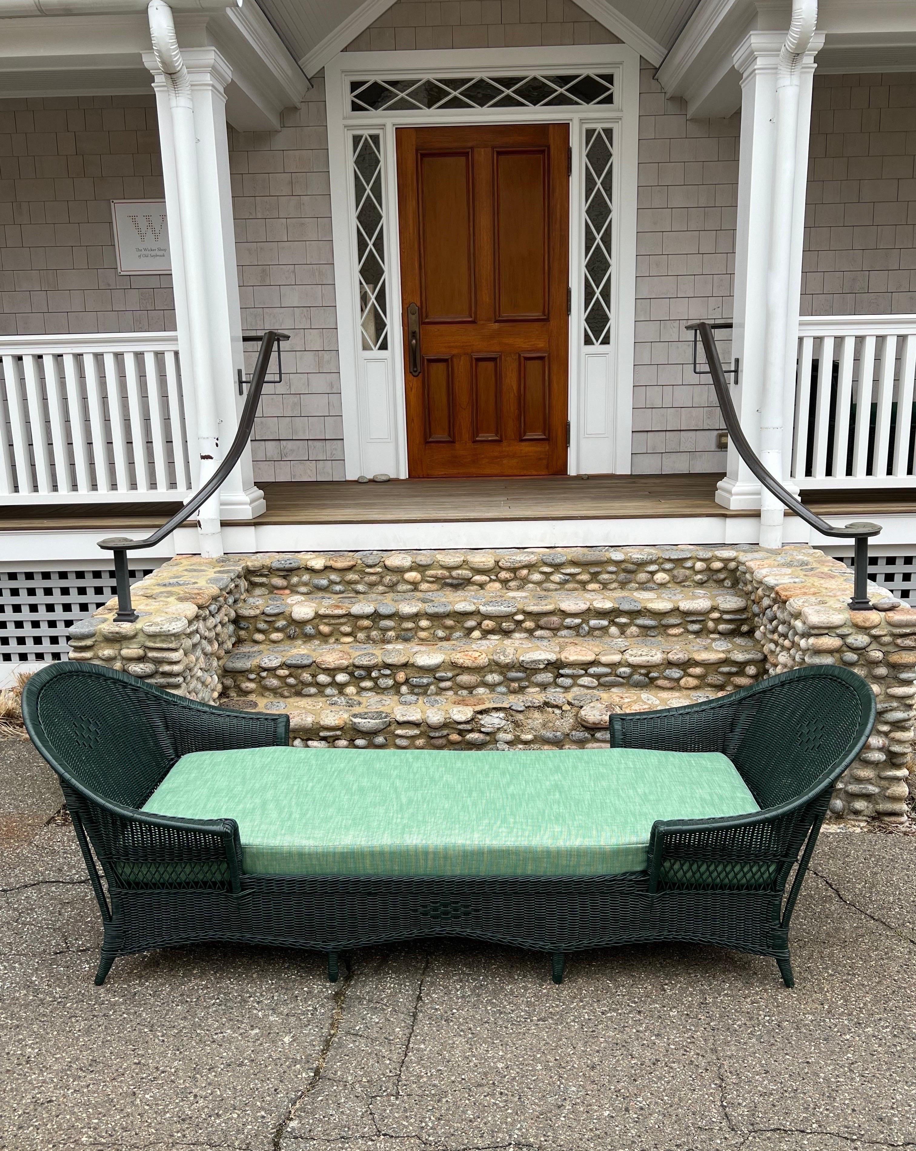This is an antique wicker chaise / daybed woven of reed and freshly painted Benjamin Moore Essex Green. A new mattress and pillows were fabricated and covered in a green Perenials fabric. Due to the exceptionally large Size it can function as a