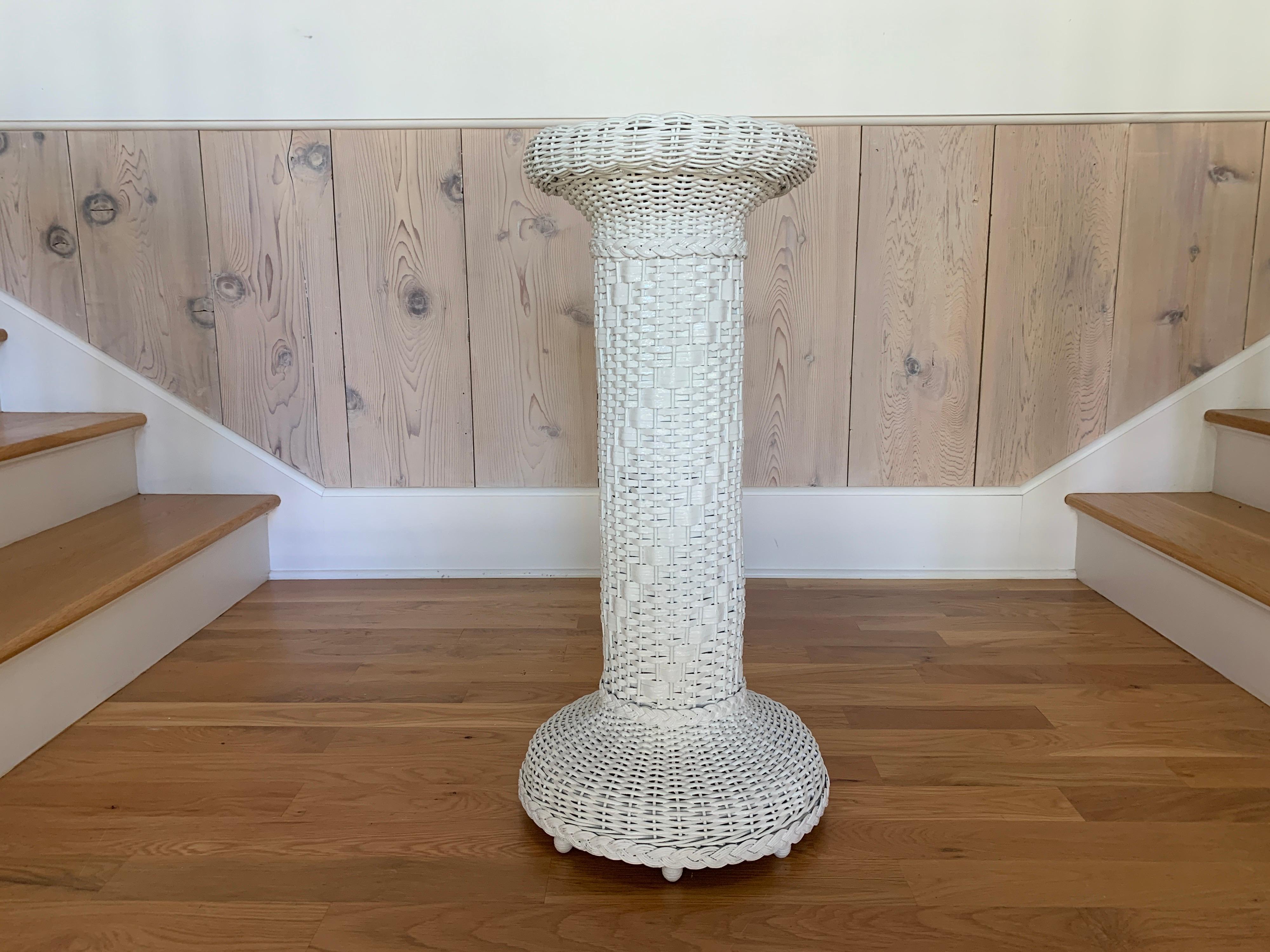 Lovely antique wicker pedestal plant stand in fresh white paint. This piece measures 31” tall, 15” wide on the floor, and 12.5” across the top. There is an 8.5” flat surface upon which you can rest a plant.