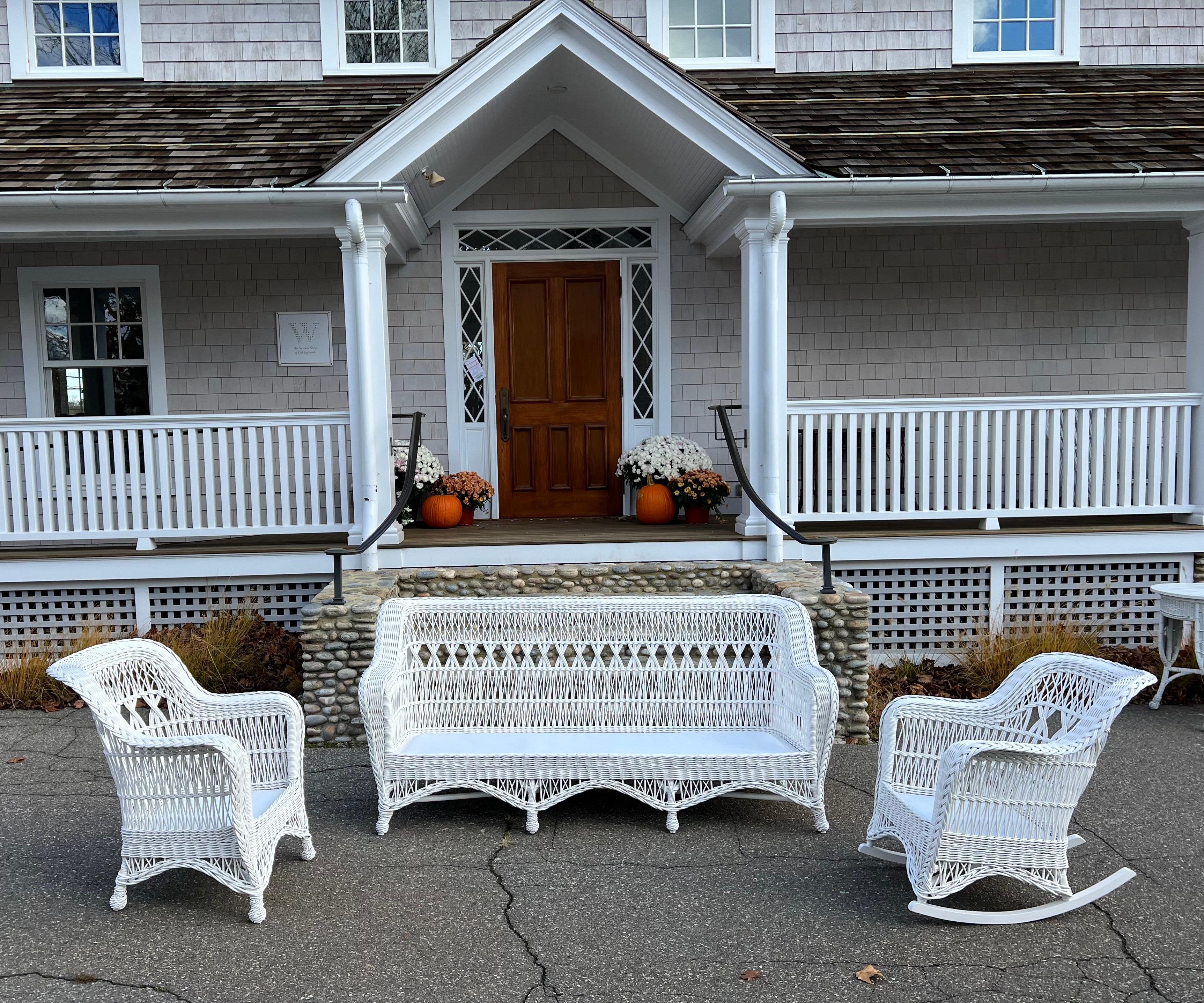 An antique three piece wicker set woven of willow and freshly painted white. Sofa measures 81” wide, 34.5” tall, 36” deep and seat platform is 12”. Chair/Rocker measure 30” wide, 34” tall, 32/34” deep with seat height of 12”.