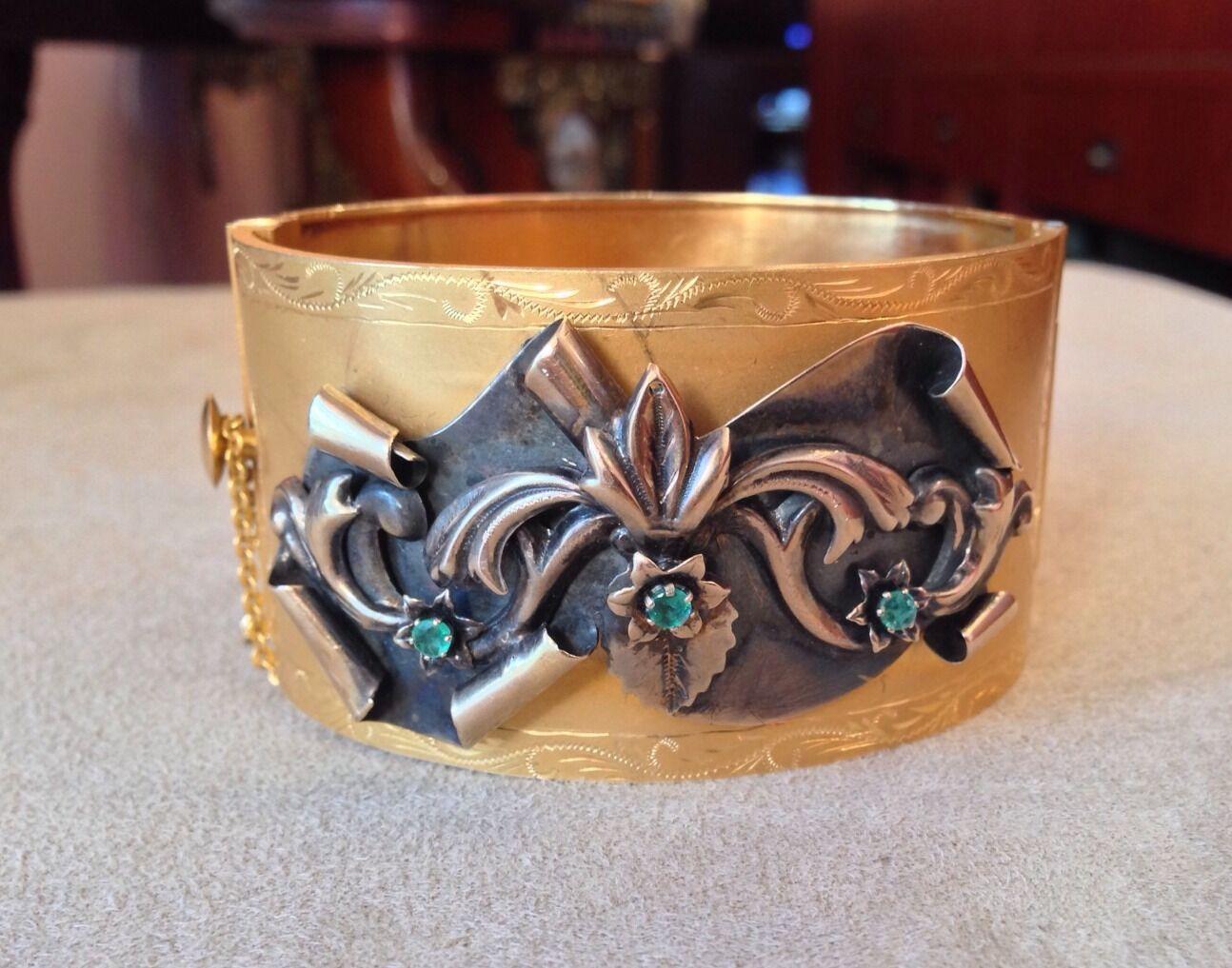 Antique Wide Gold Bangle Bracelet in 12K Yellow Gold with Emeralds

Beautiful Antique Bangle Bracelet features a raised flower motif with leaves and a floral spray design on one side with 3 Green Emeralds in the center of each flower set in 12k