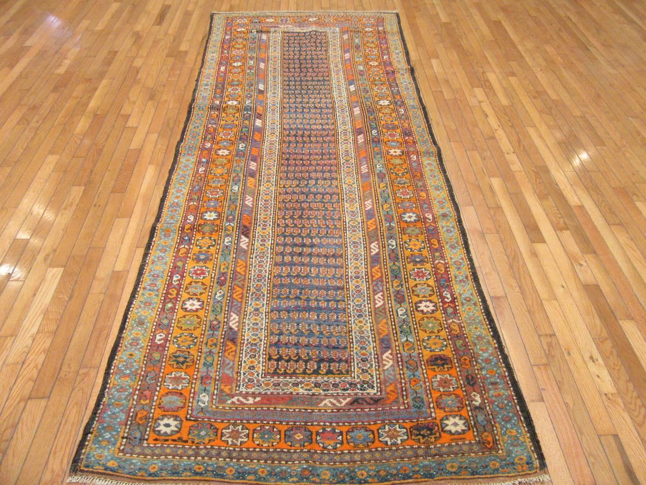 This is an antique hand knotted rug from the Kurdish region of western Iran. This rug is made with all wool colored with natural dyes in around the turn of the century. It has a detailed repetitive paisley motifs on a dark blue color background